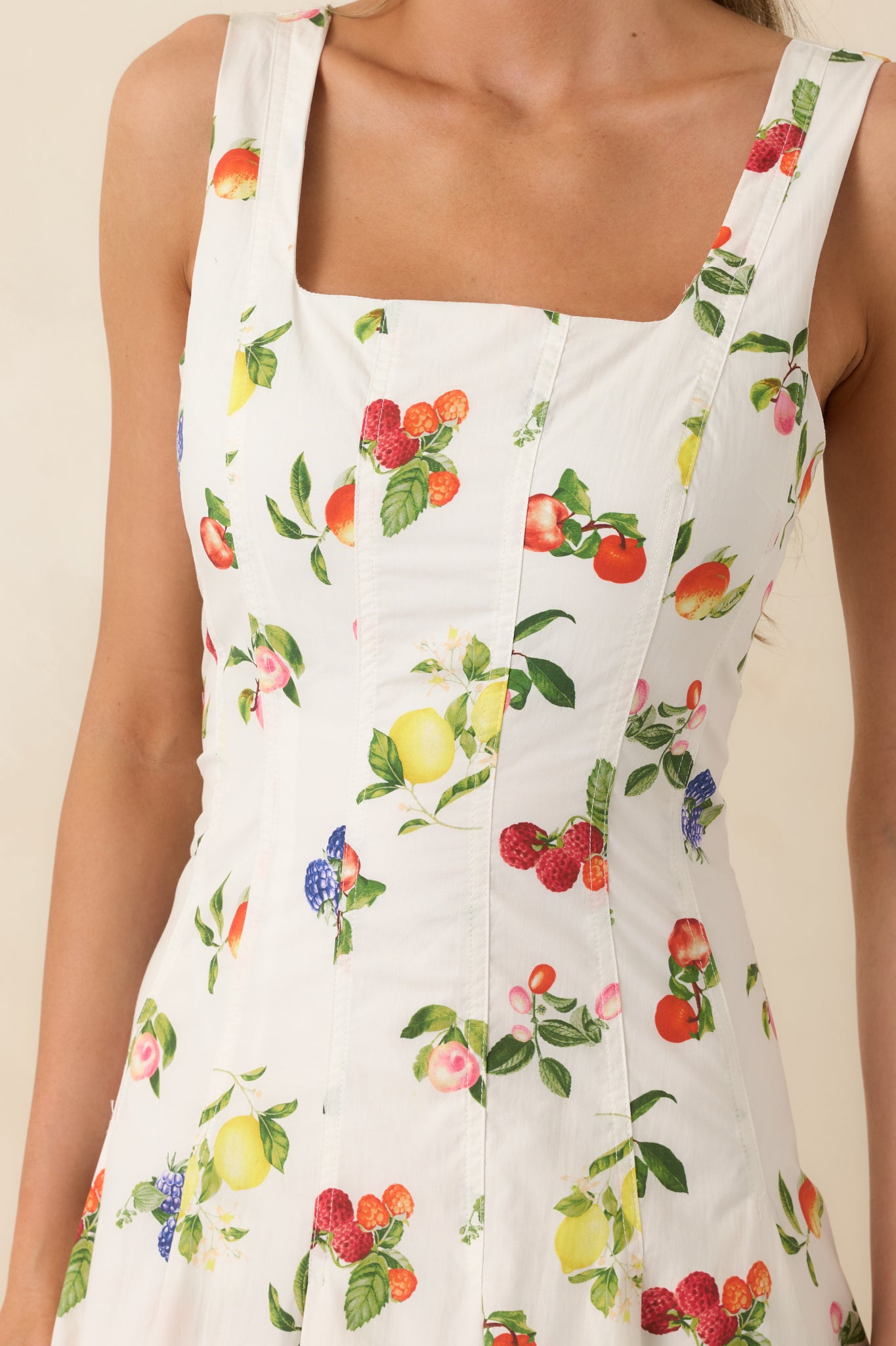 Close-up of cotton dress fabric showing colorful fruit print and fitted vertical bodice seams