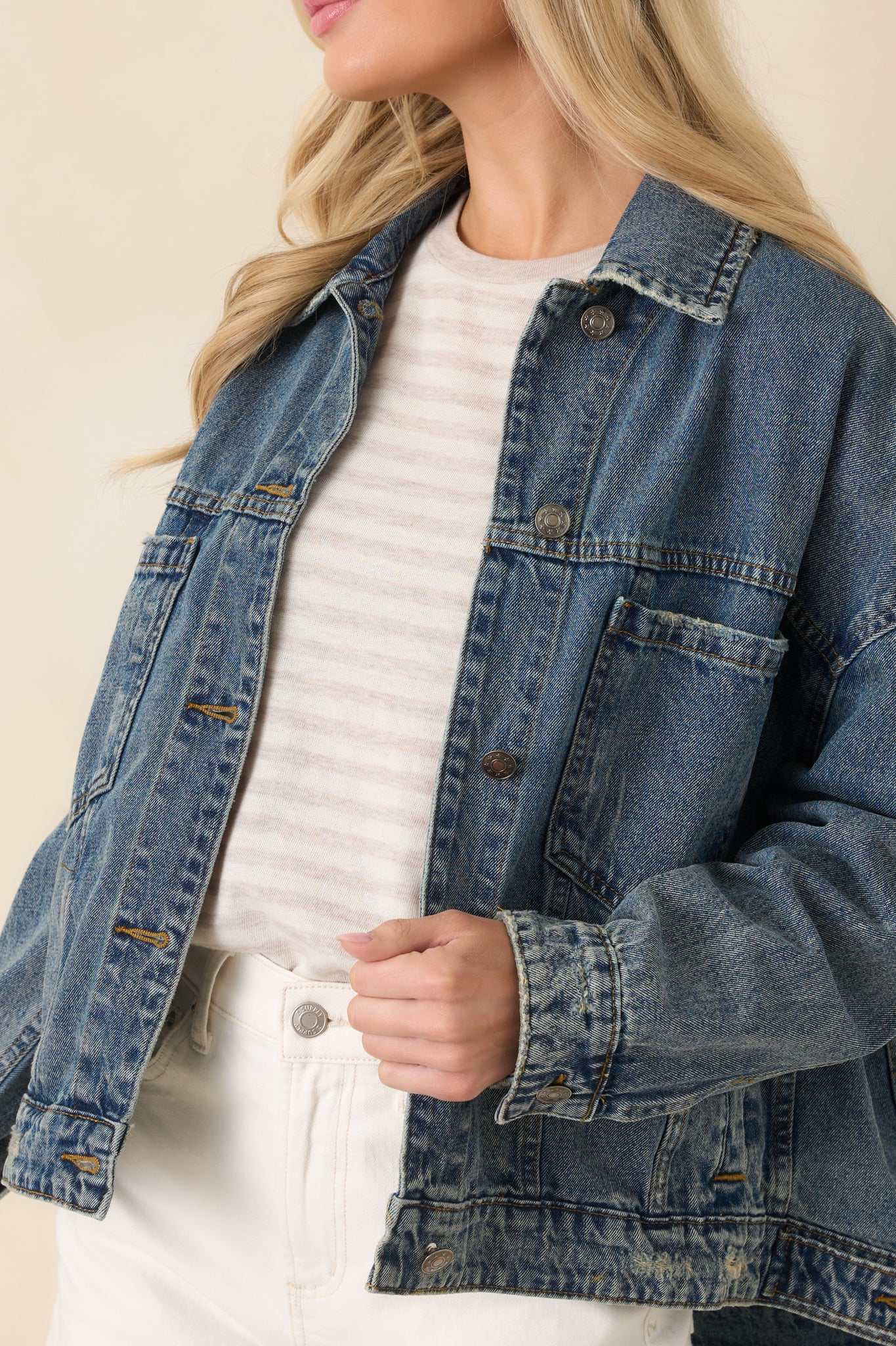 Close-up of denim jacket showcasing button hardware, pocket detailing, and subtle fading in the fabric.
