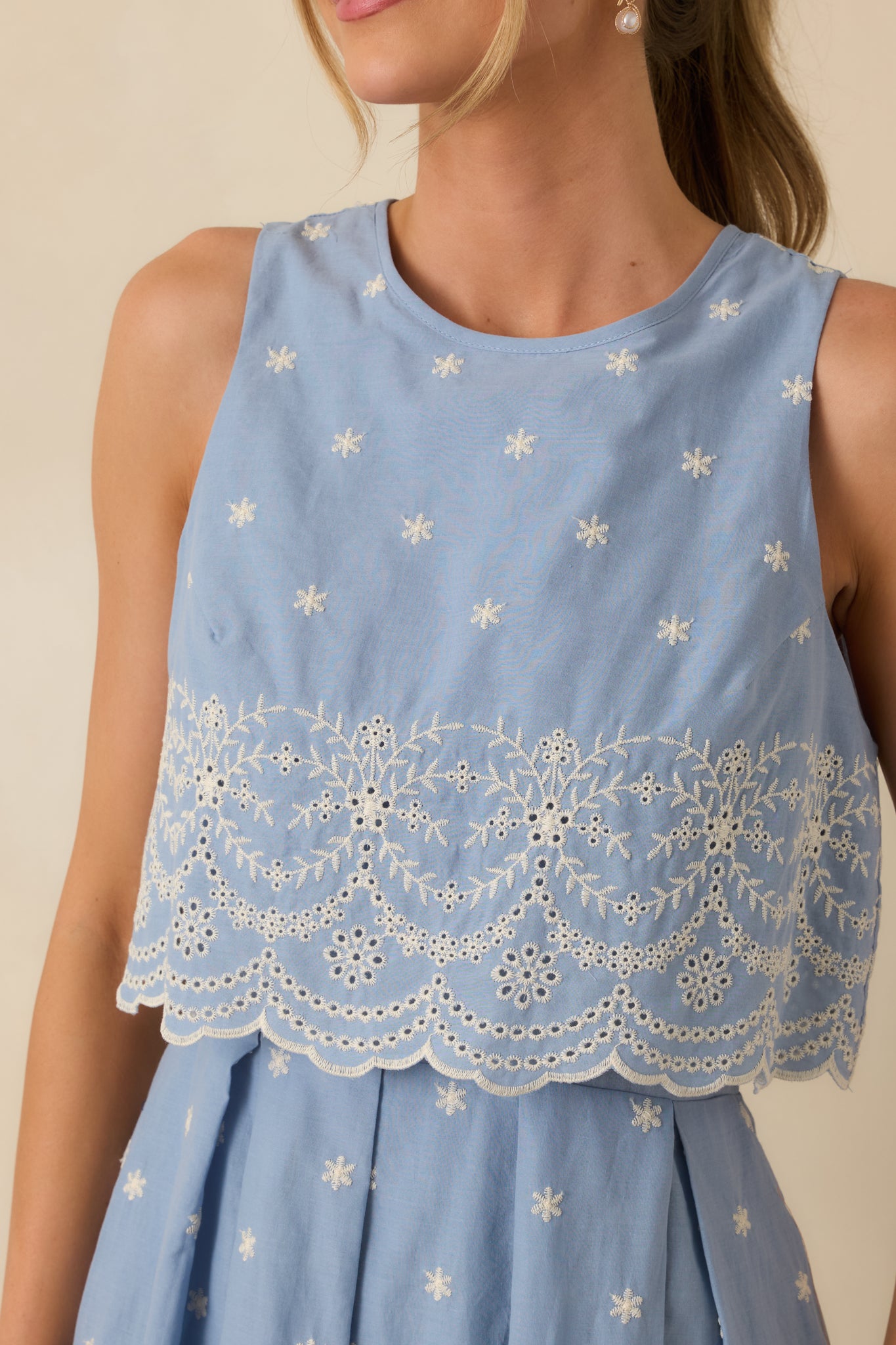 Close-up of embroidered detailing and scalloped lace trim on bodice and overlay of light blue dress.