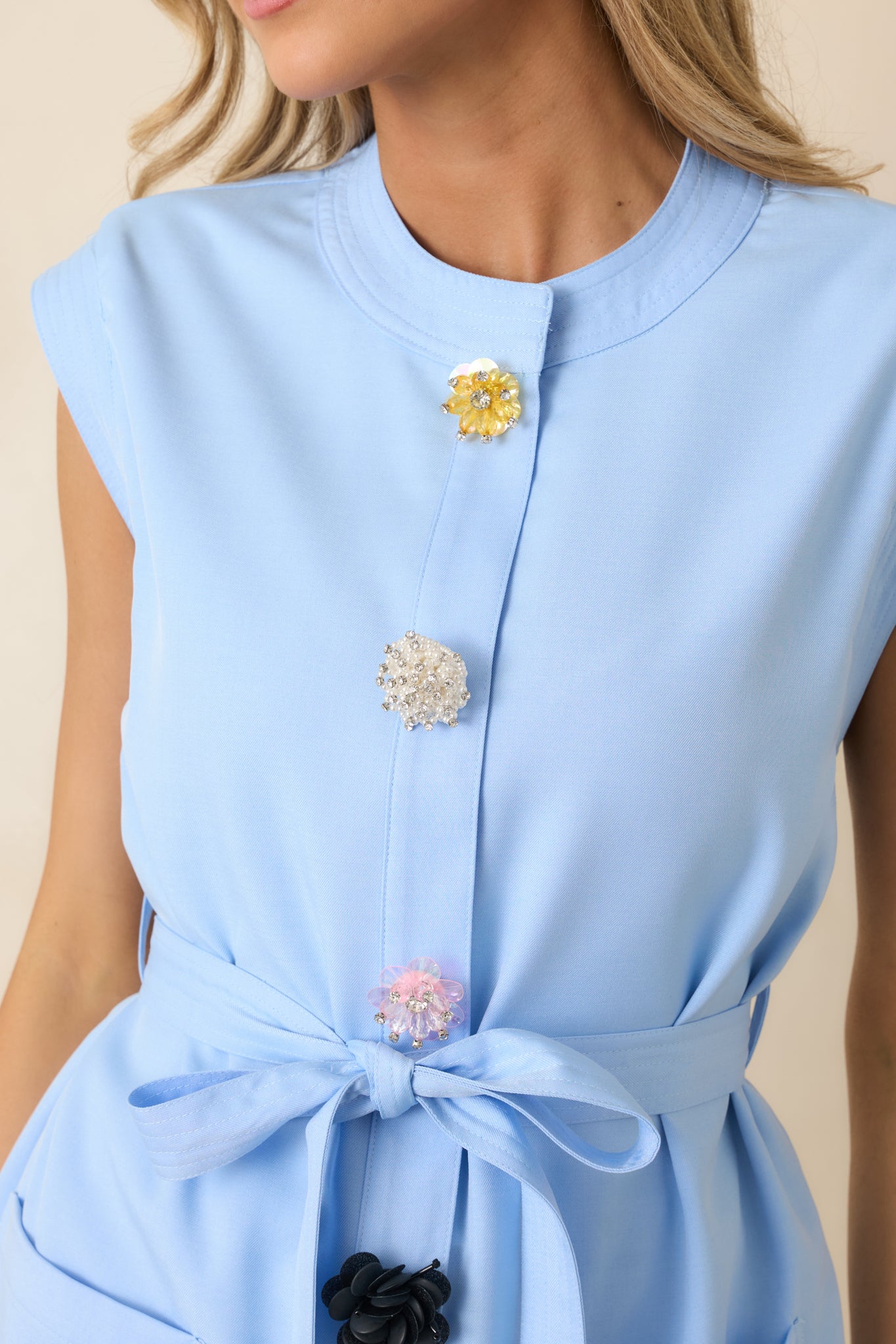 Close-up of floral-inspired buttons on soft light blue tailored top