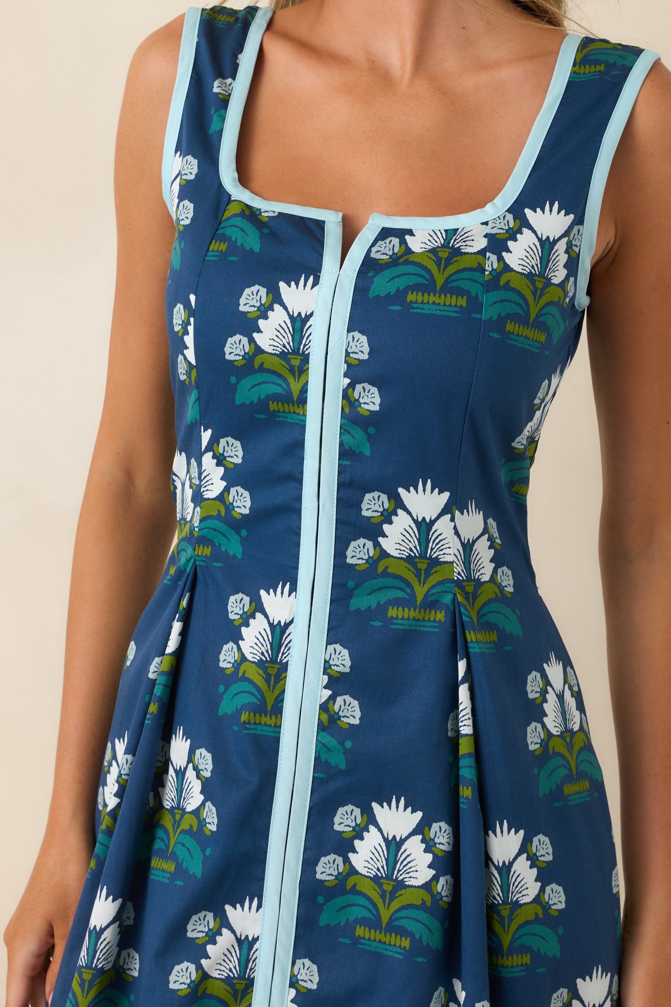 Close-up view of the floral motif, contrast neckline trim, and pleated skirt detailing.