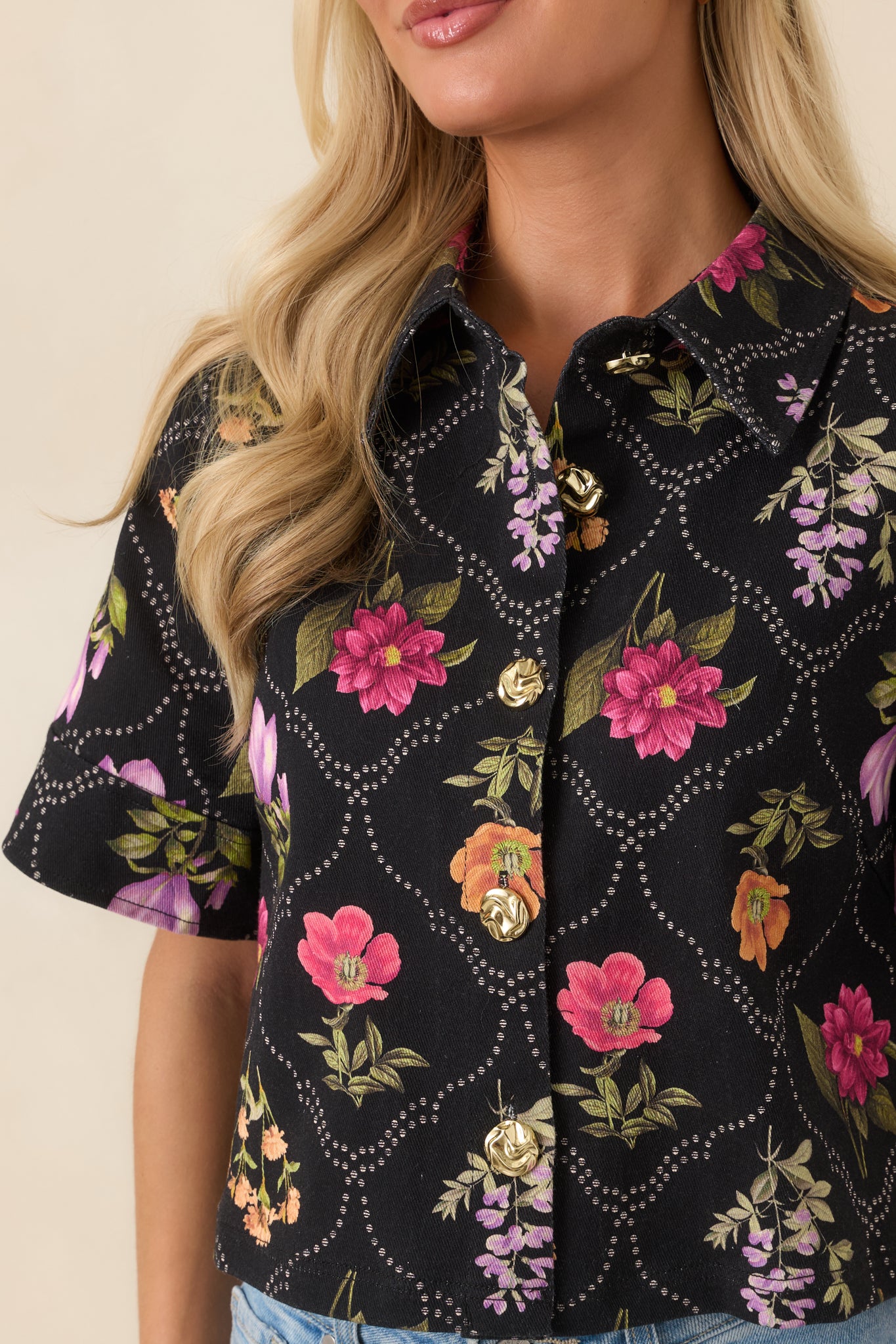 Close-up view of the floral print, dotted lattice pattern, and sculptural gold-tone button details.
