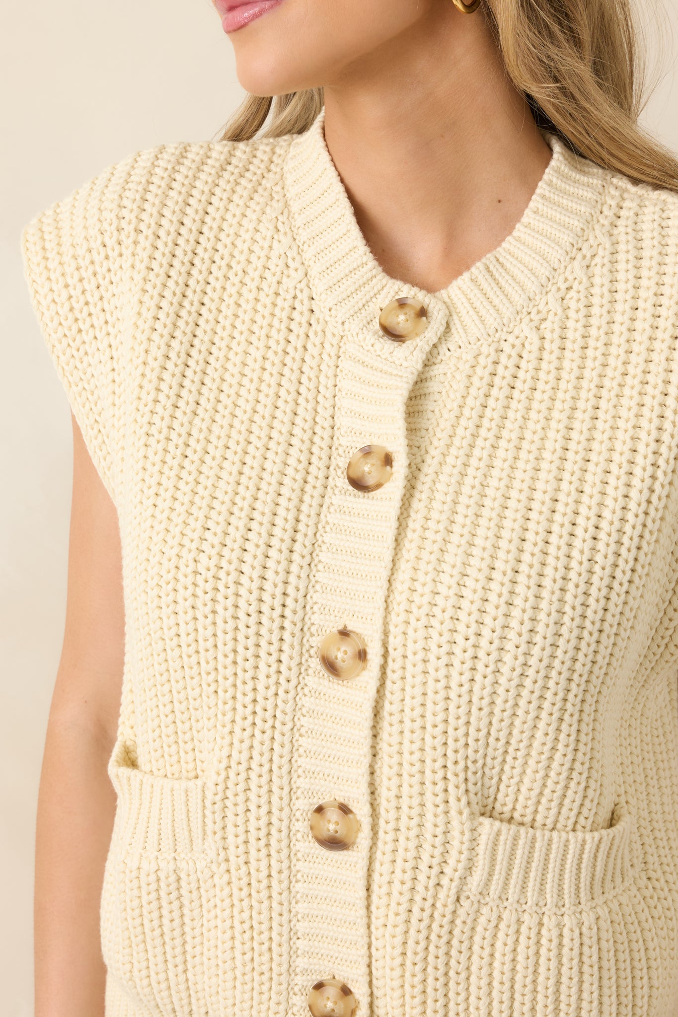 Close-up of marbled button-front closure and ivory cotton knit fabric, showing textured detail and ribbed edging.