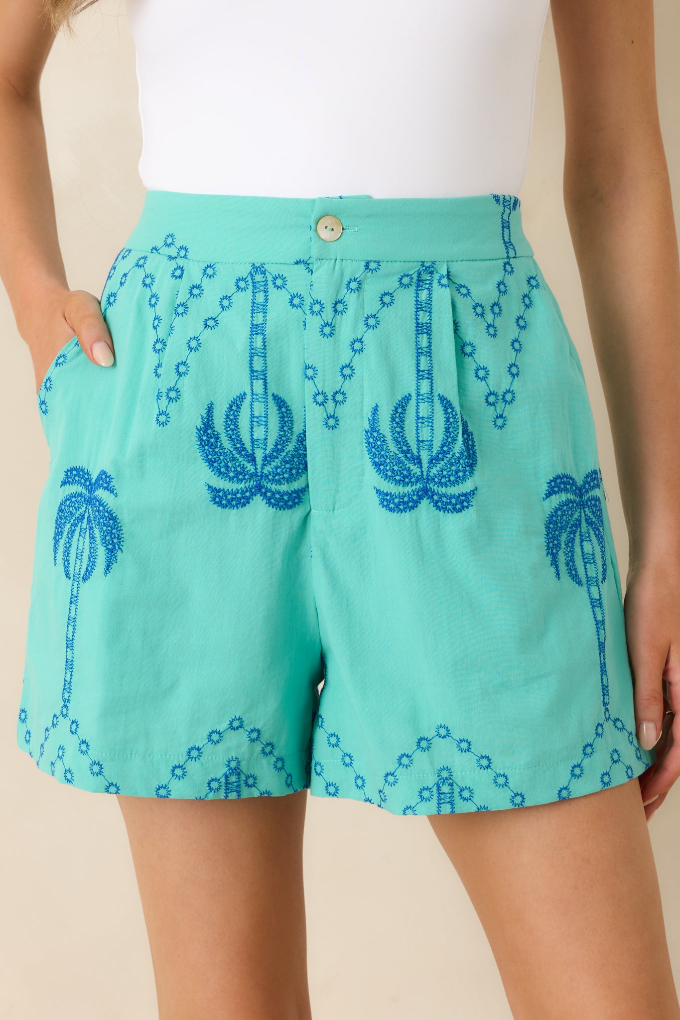 Close-up of palm tree embroidery with fine stitching on lightweight cotton fabric.