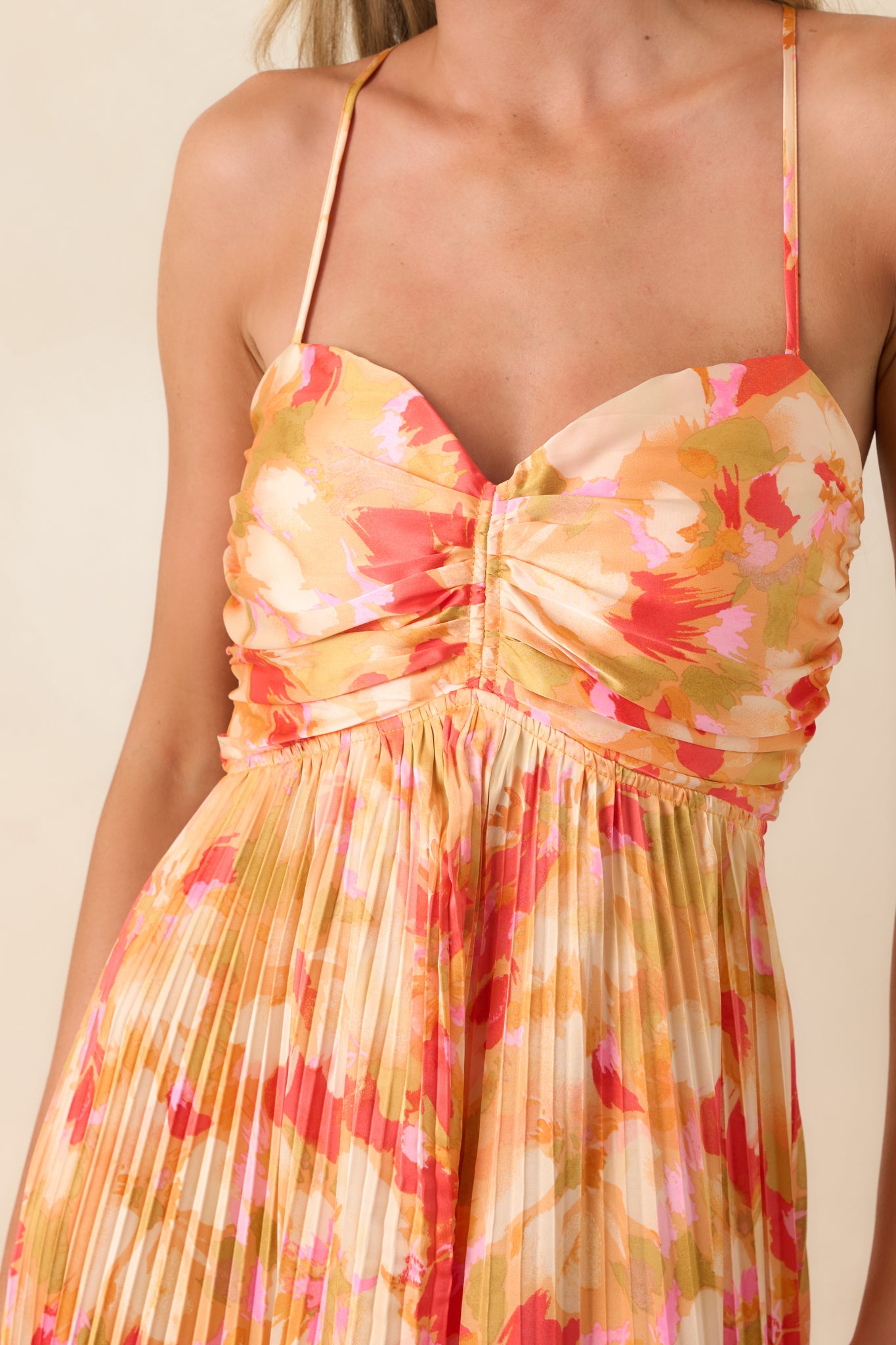 Close-up of pleated satin-like fabric with soft sheen and ruched bodice detailing on flowing maxi dress.