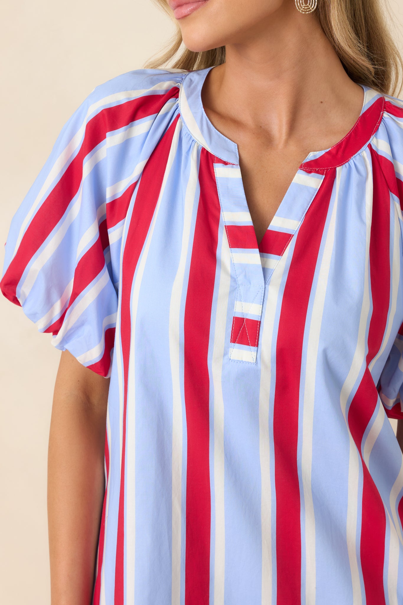 Close-up of red and light blue striped mini dress showing the puff sleeve, soft cotton texture, and stitching details