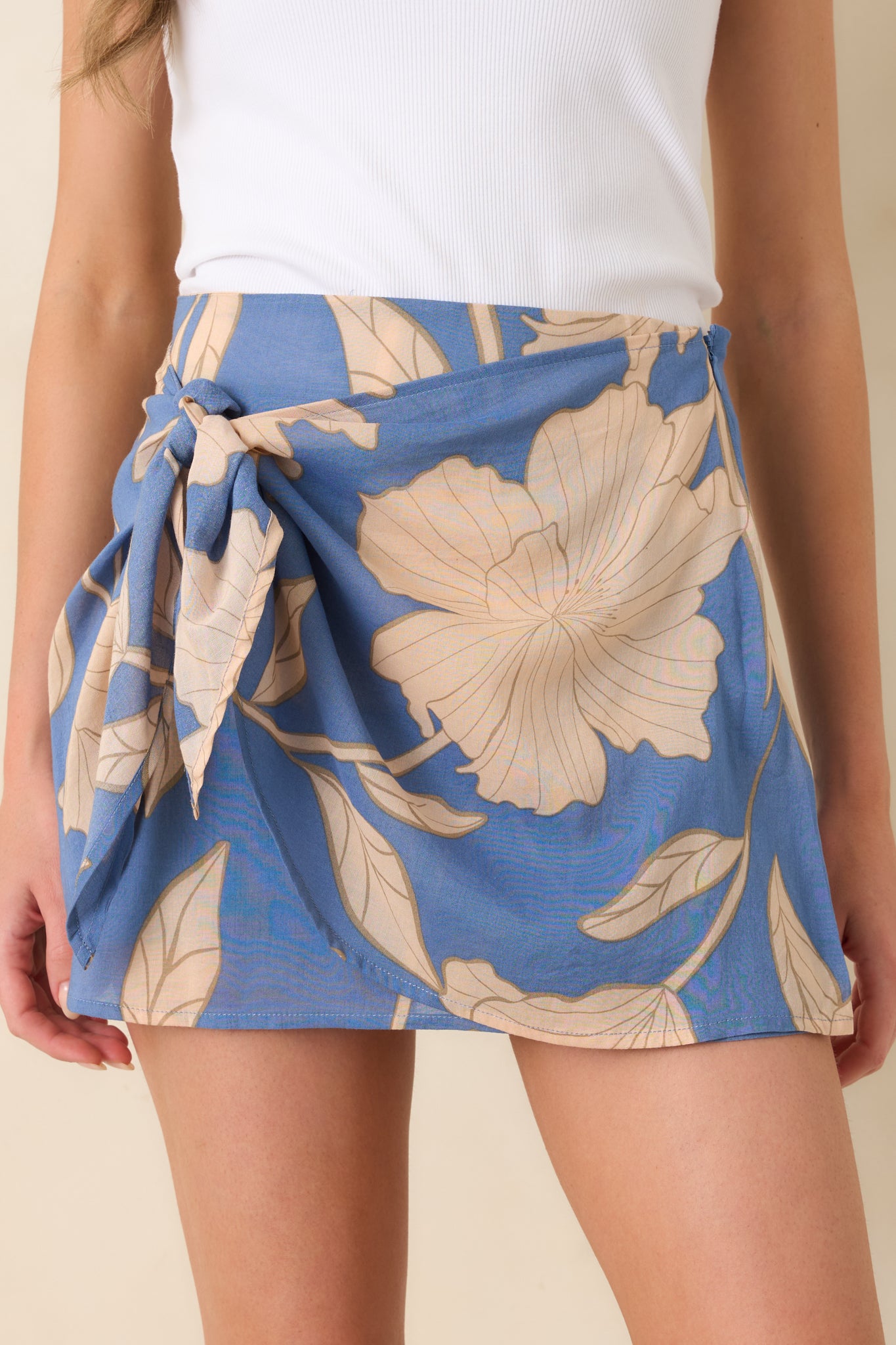 Close-up of side tie knot and wrap construction with oversized neutral floral print on lightweight blue fabric.