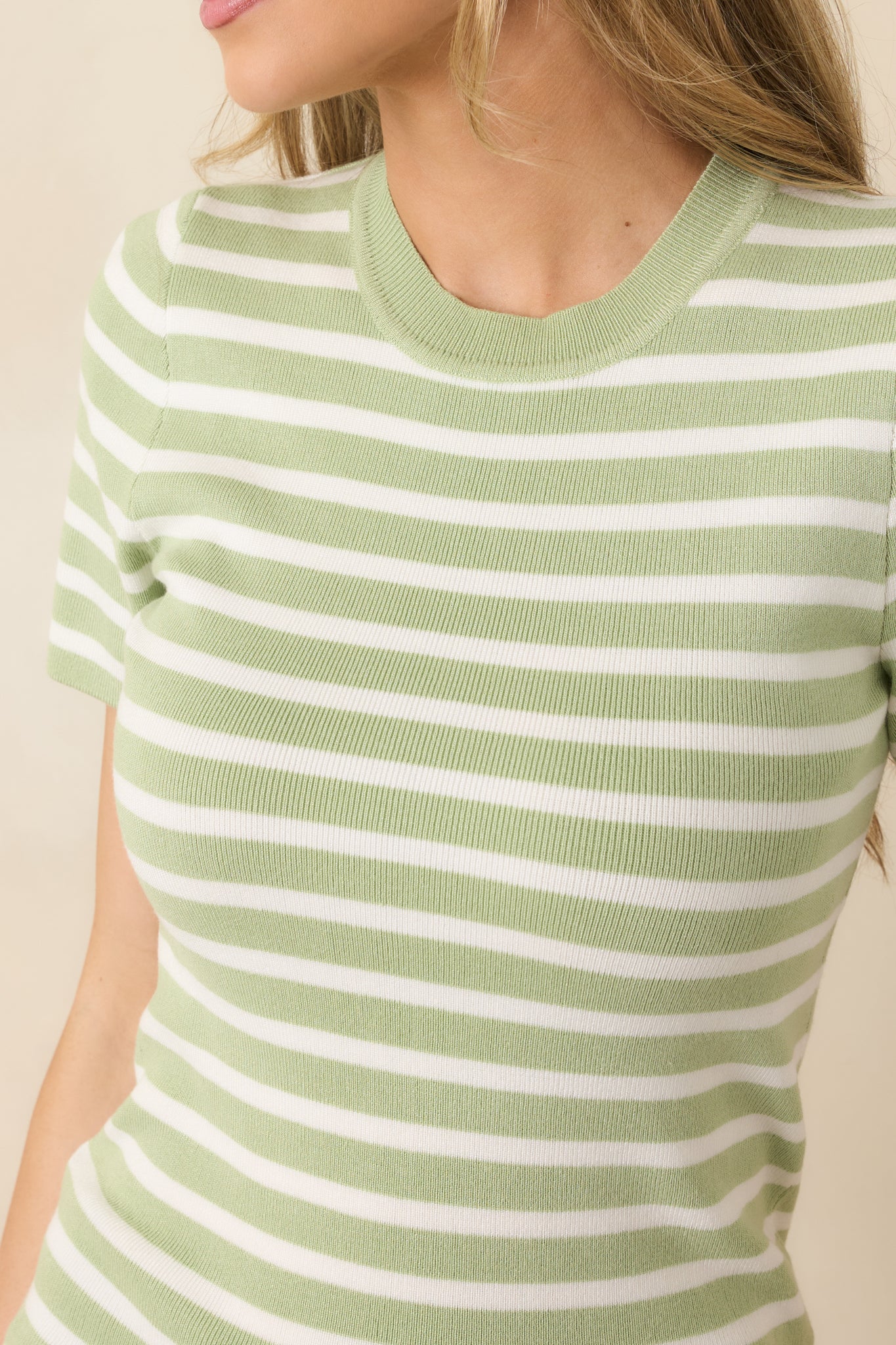 Close-up of soft knit fabric featuring light green and ivory horizontal stripes with fine texture and clean stitching.