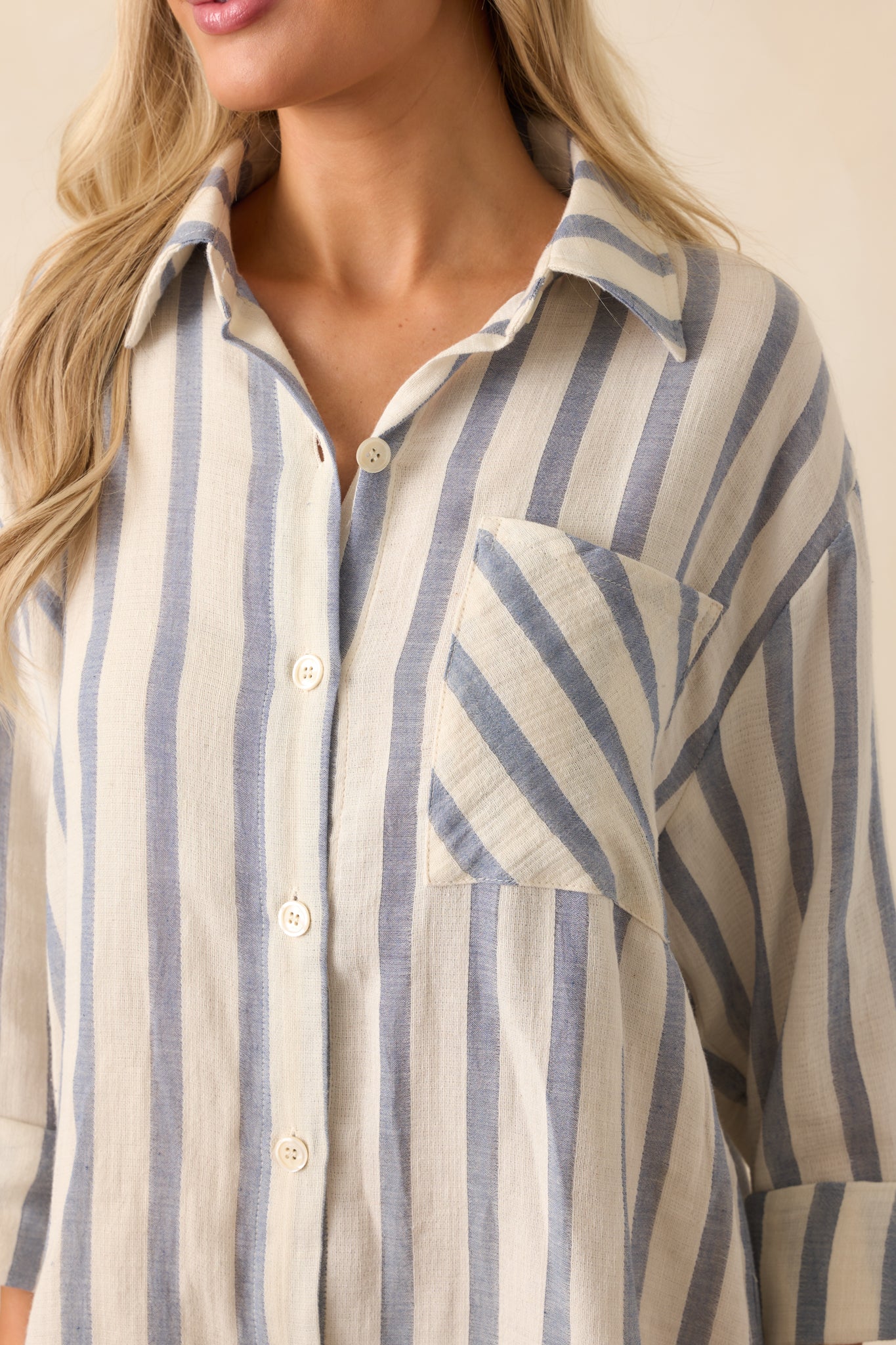 Close-up of the blue and white cotton fabric and functional button cuff on the sleeve.