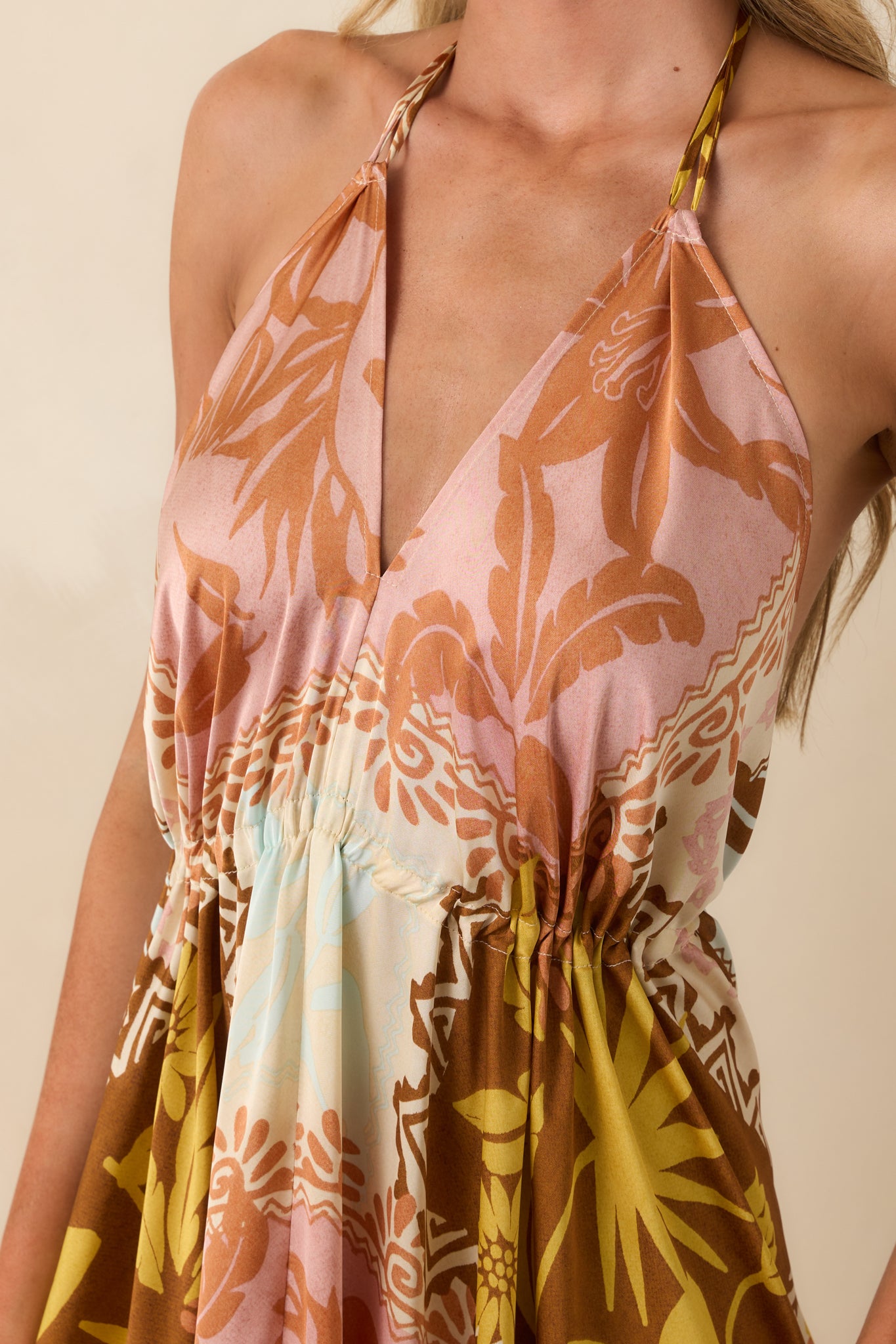 Close-up of the halter v-neckline showing the multicolor patchwork print and smooth satin-like texture of the fabric.