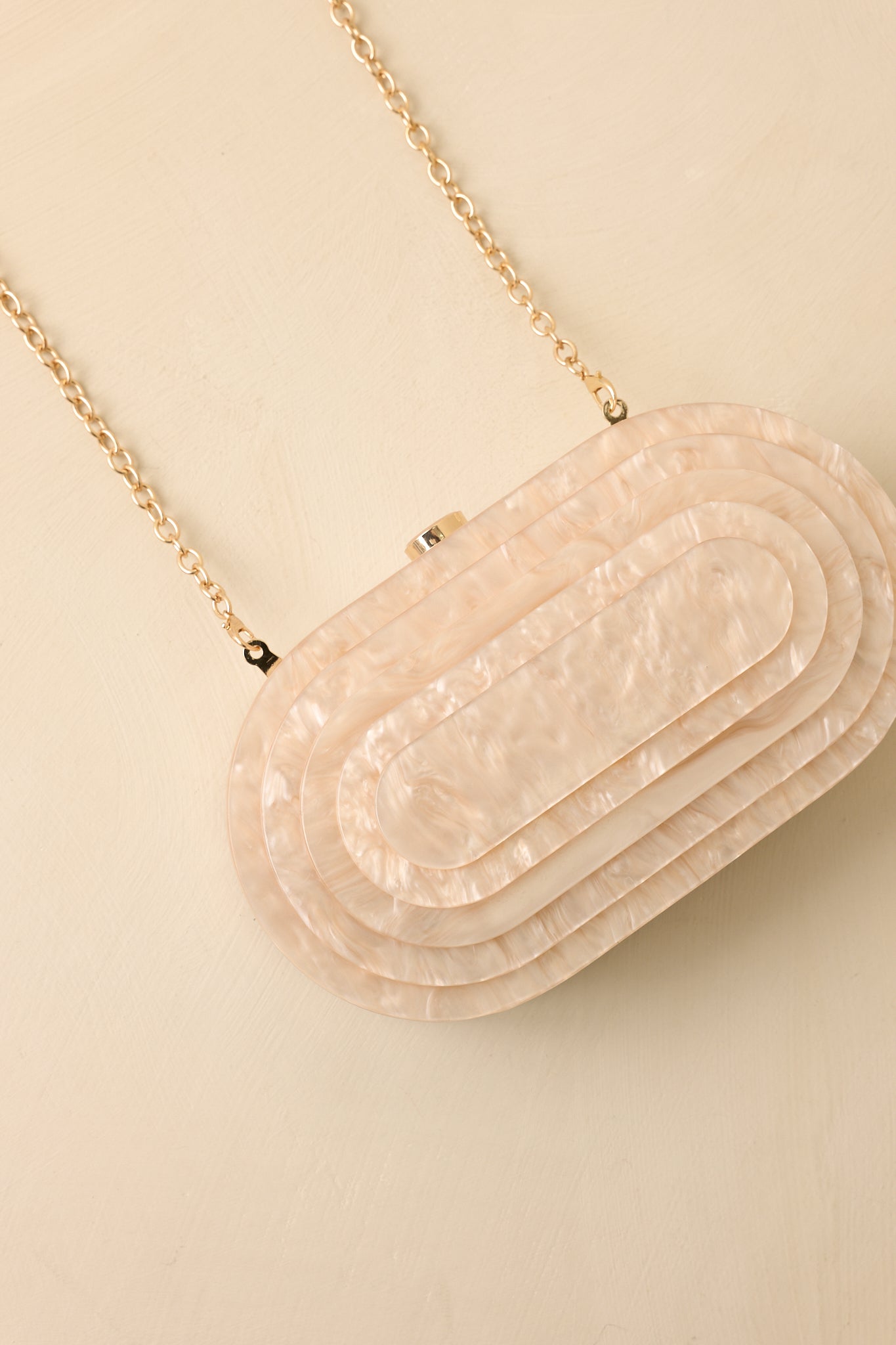 Close-up of the smooth pearlescent finish, top clasp closure, and elegant oval clutch detailing.