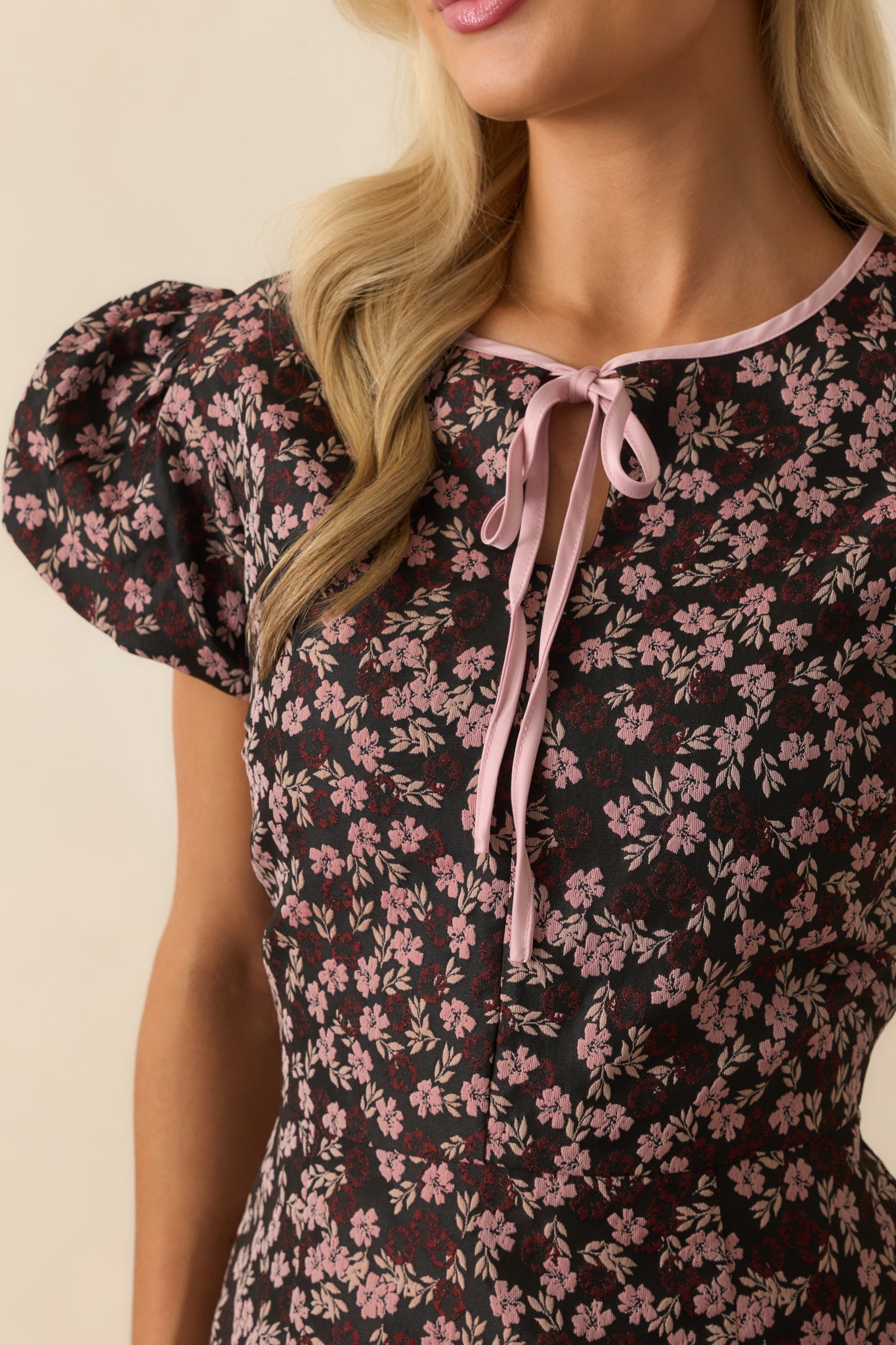 Close-up of the pink floral jacquard and self-tie bow neckline on the mini dress.