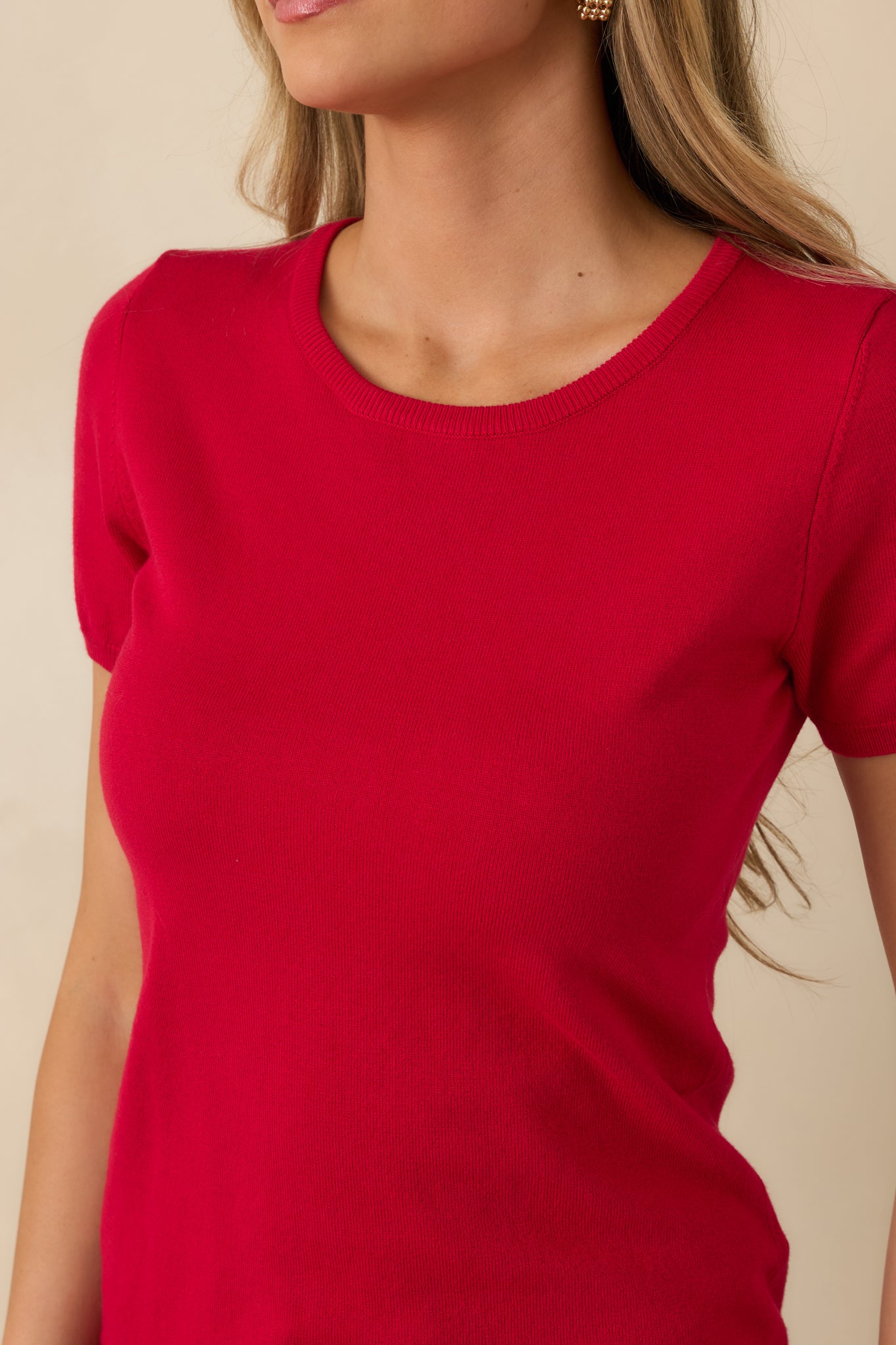 Close-up of red sweater top showing soft knit fabric, ribbed hem, and sleeve edge.