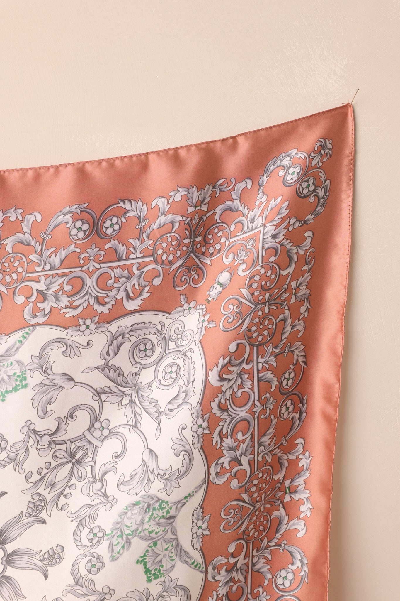 Close-up of the scarf, highlighting the ornate grey and floral motif, rose pink border, and satin finish.