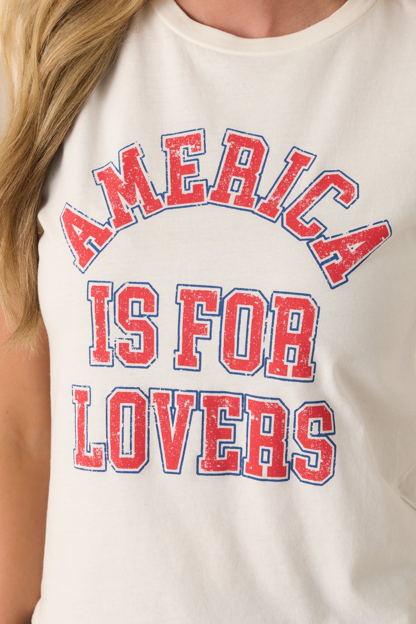 Extreme close-up of the screen print graphic, capturing the crisp red and blue lettering and the weave of the ivory jersey fabric.