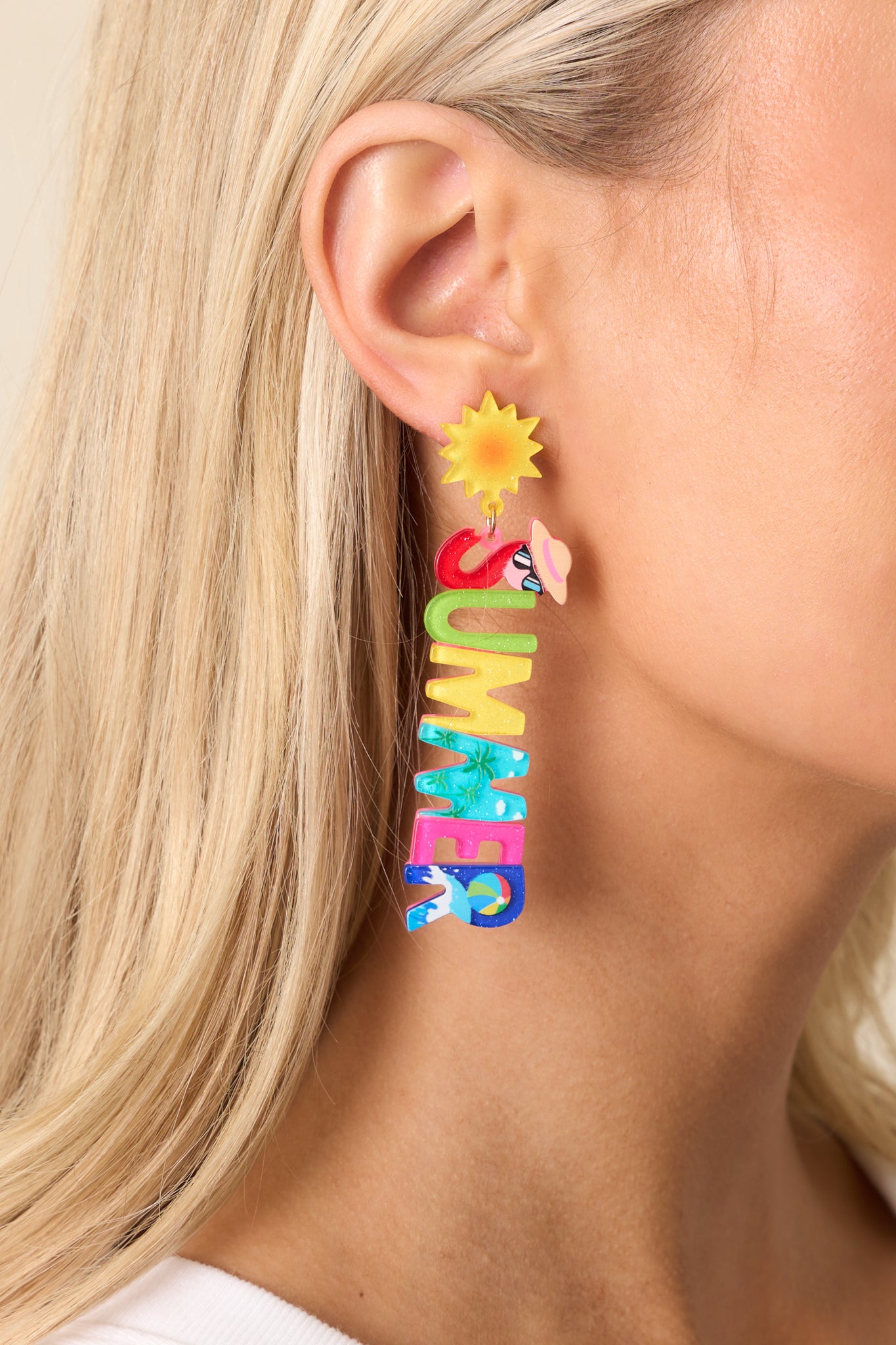 A close-up section of the earrings, focusing on the colorful acrylic lettering spelling out "SUMMER" with unique beach-themed prints.