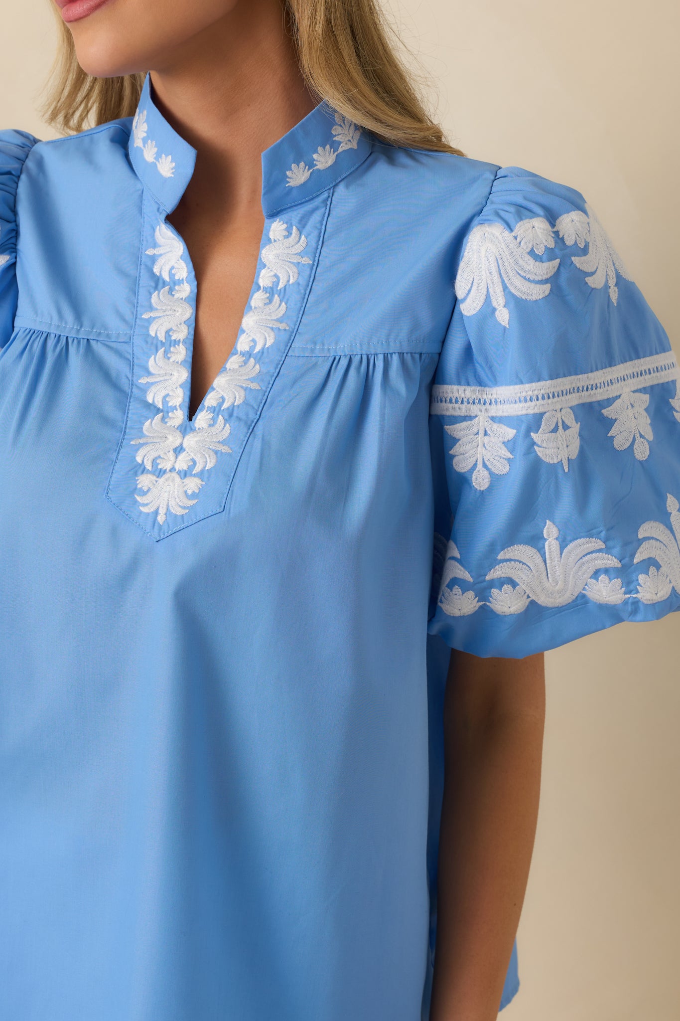 Close-up of the blue top showing the white embroidered accents and gathered puff sleeve detail.