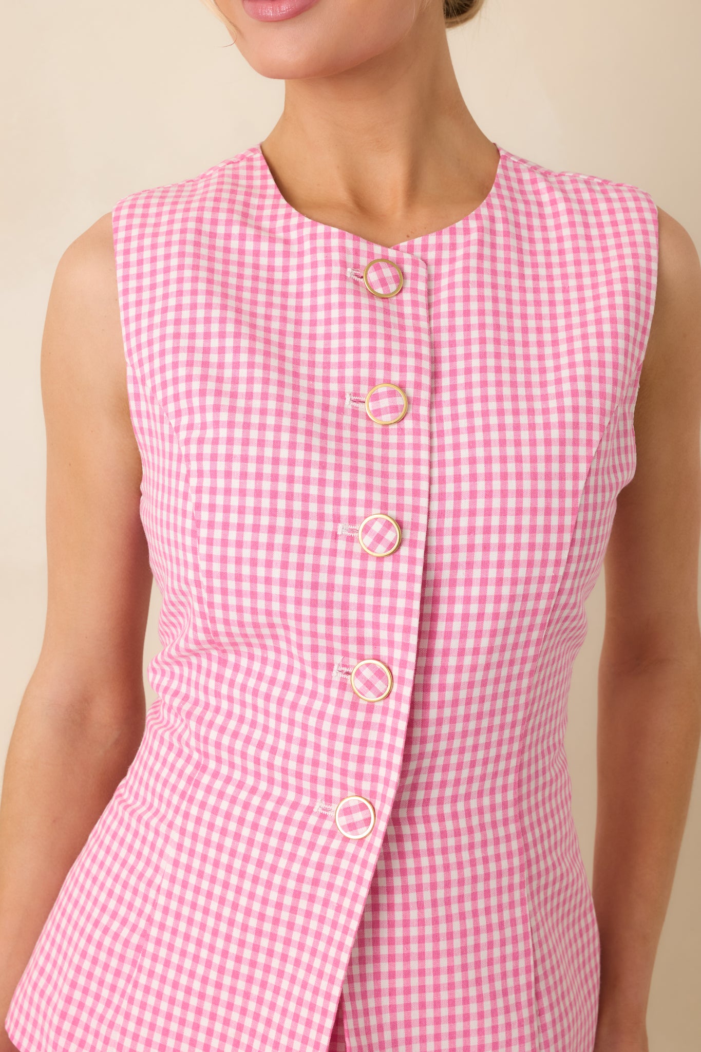 Close-up of the pink gingham romper showing the button closure, fabric texture, and fine gingham pattern.