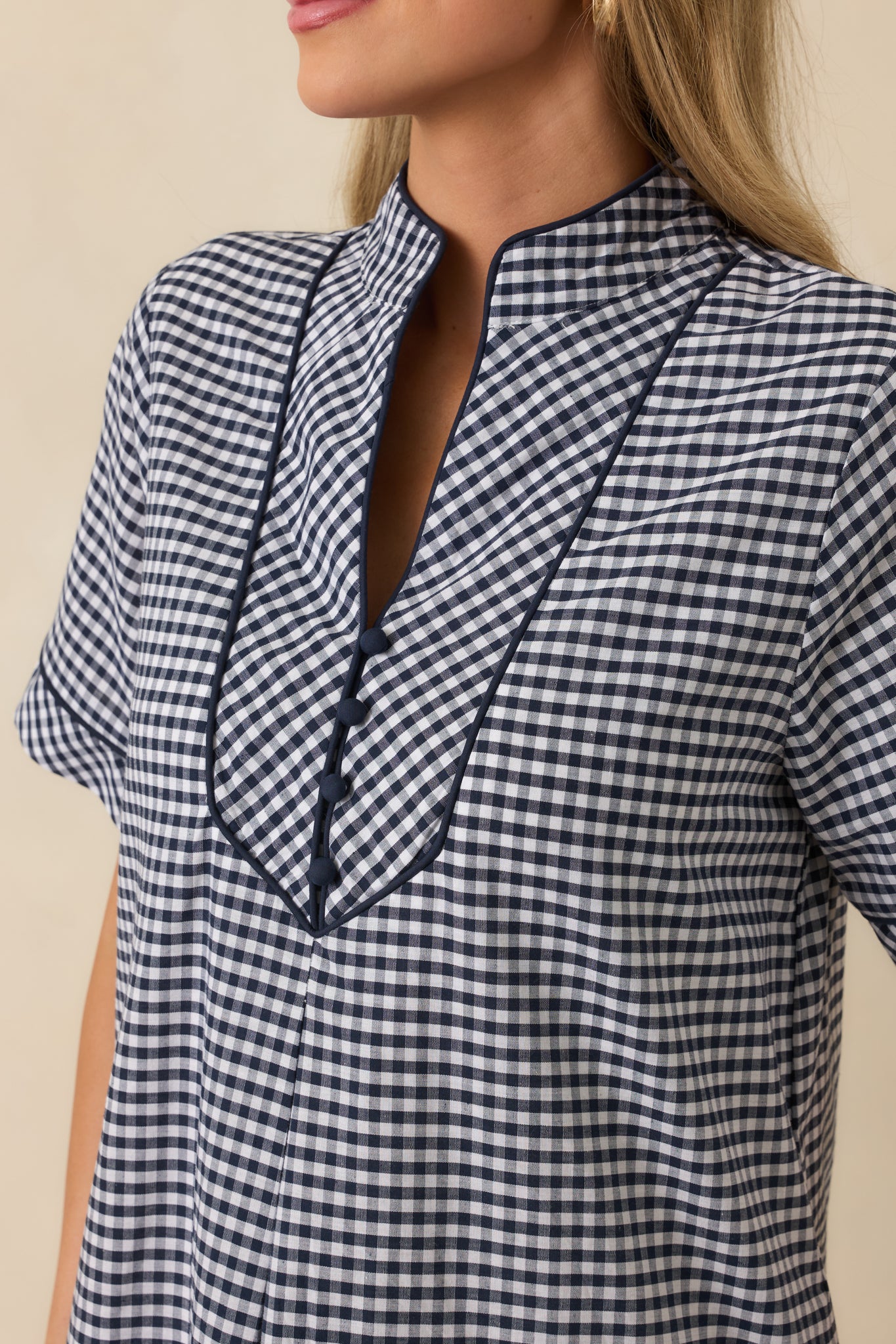 Close-up of the navy gingham fabric showing the contrast-trimmed V-neckline and fine, lightweight texture.