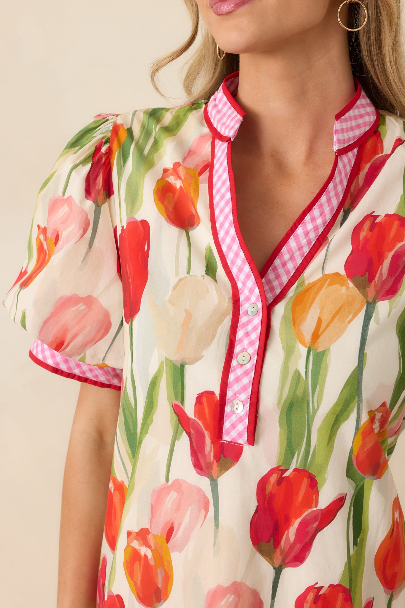 Close-up of the red mini dress showing the gingham trim, tulip print, and fabric tie-back detail.