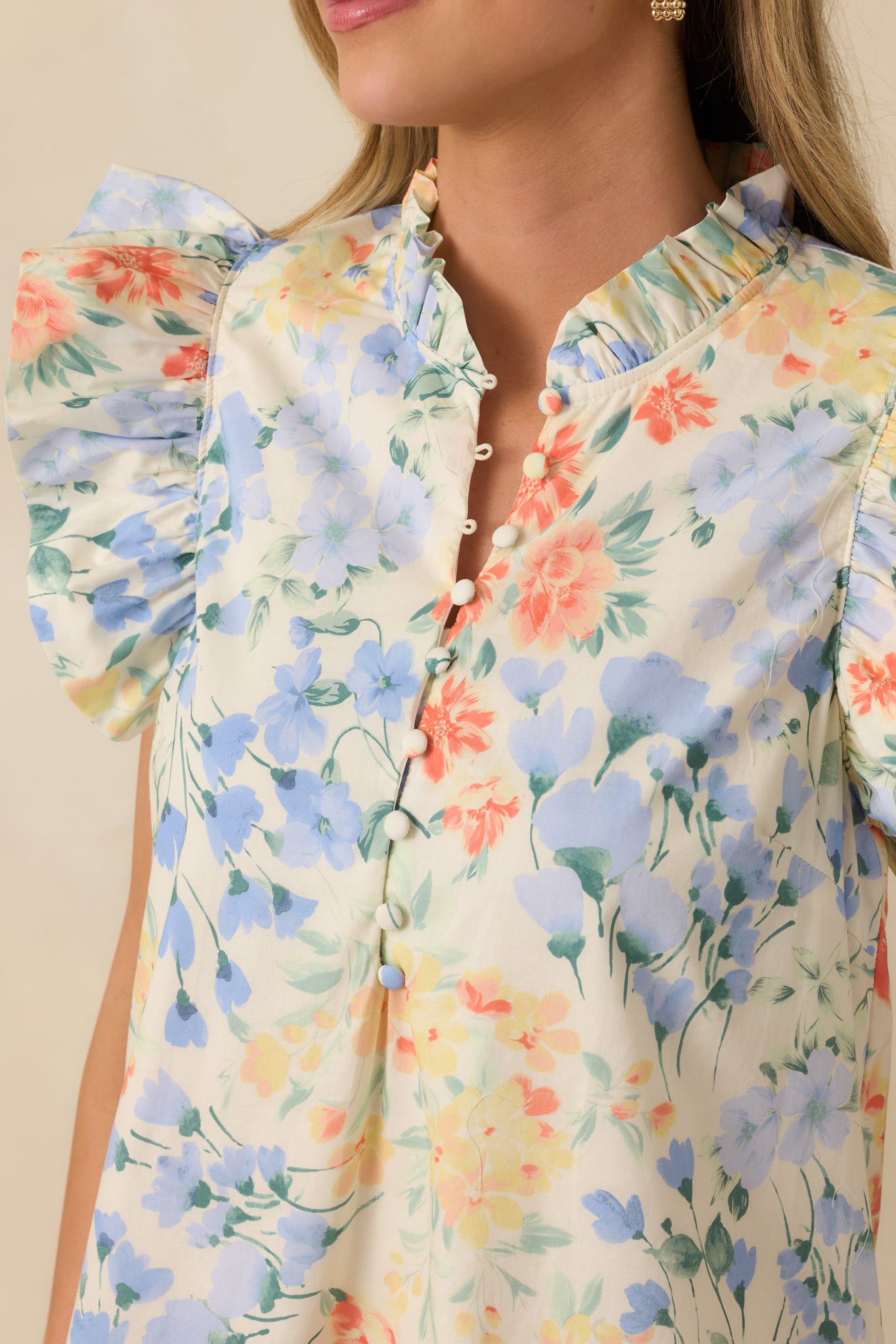 Close-up of the ivory midi dress showing the pastel floral pattern, split neckline, and flutter sleeve texture.