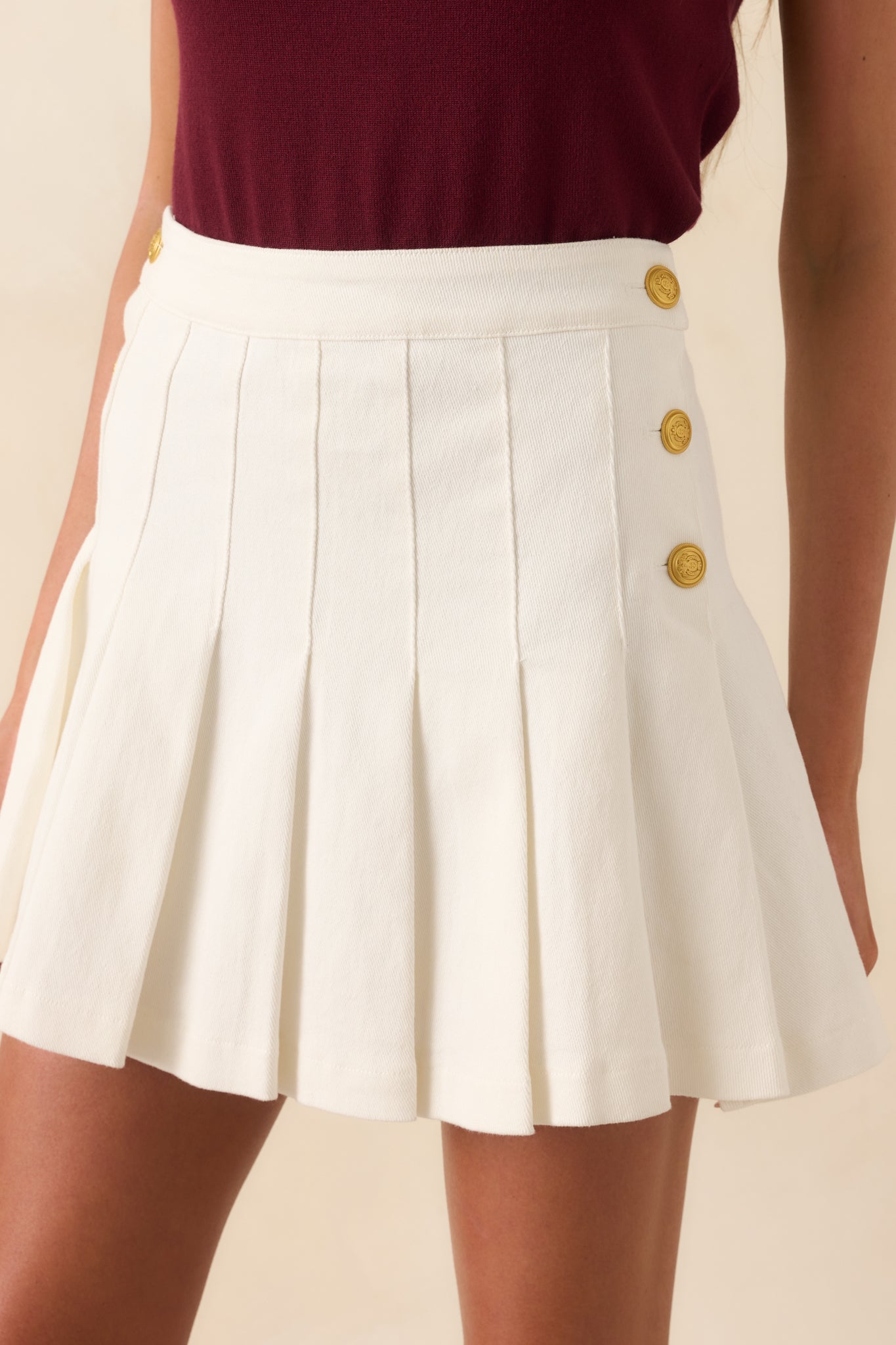 Close-up of one side of the skirt showing the detailed embossing on the gold buttons and the grain of the denim fabric.