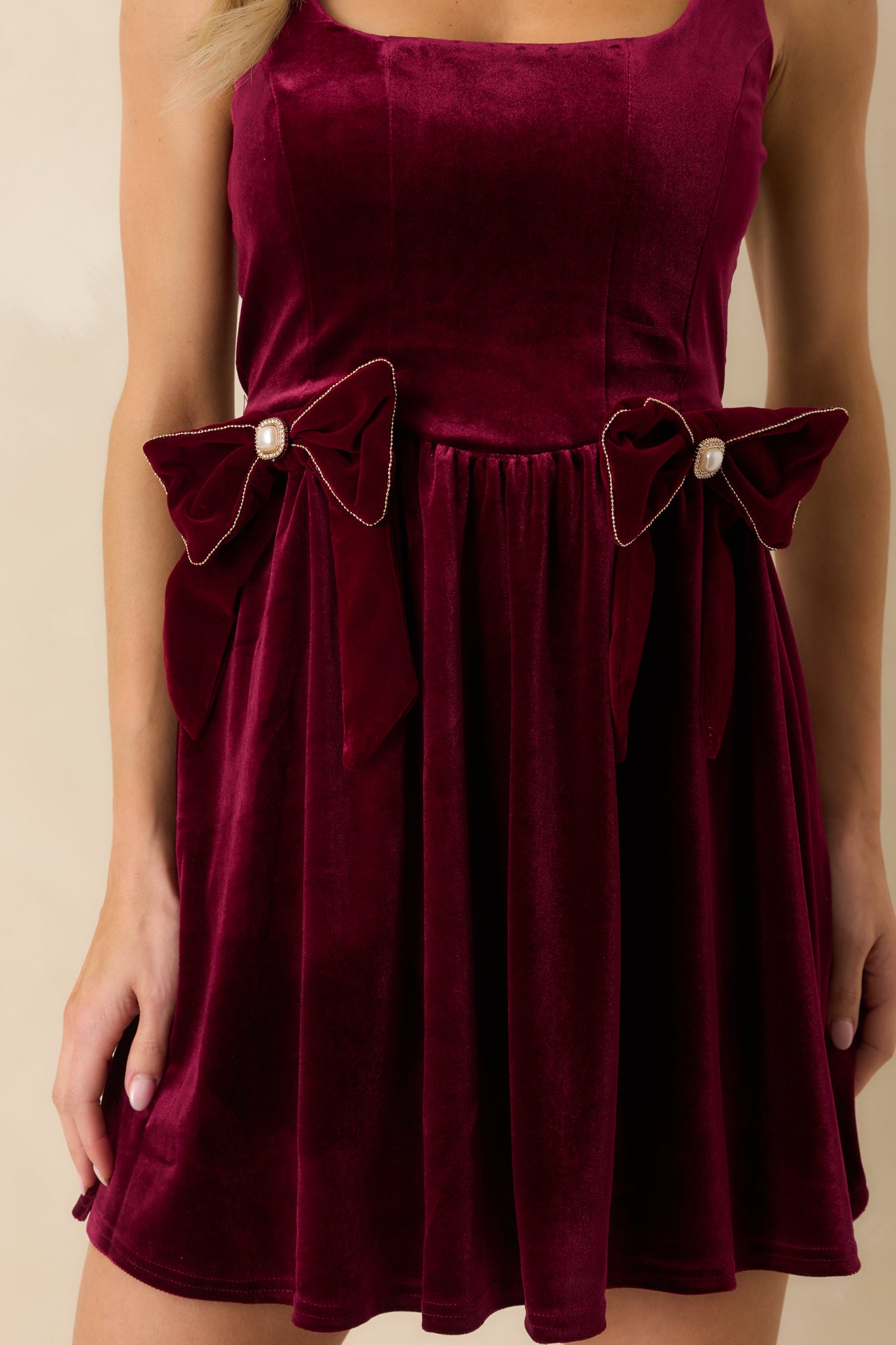 Detailed close-up of decorative velvet bow with faux pearls, smooth velvet fabric, and gathered skirt.