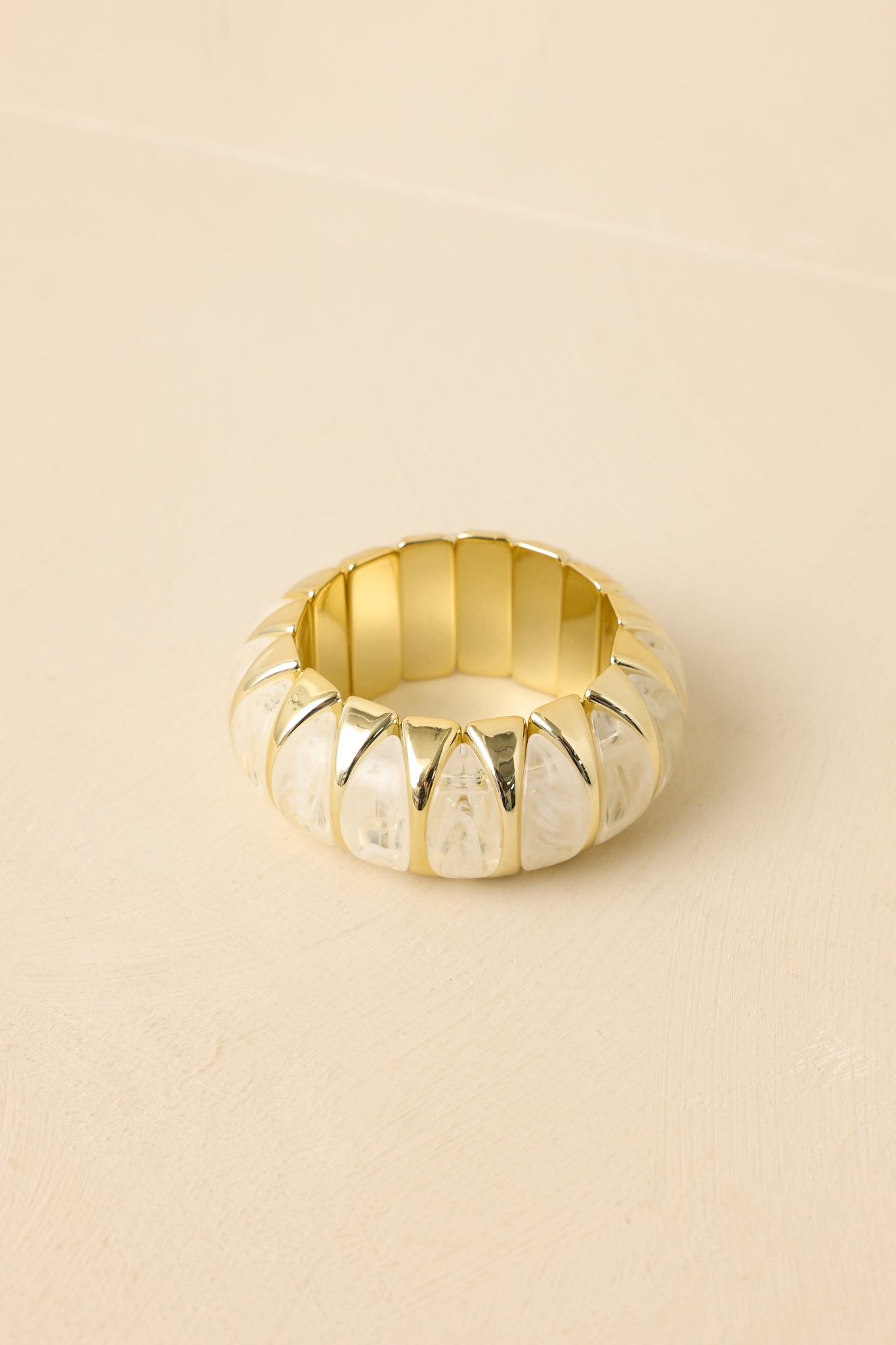Close-up of white and gold bracelet highlighting marbled bead texture, smooth gold cradled settings, and stretch band construction.