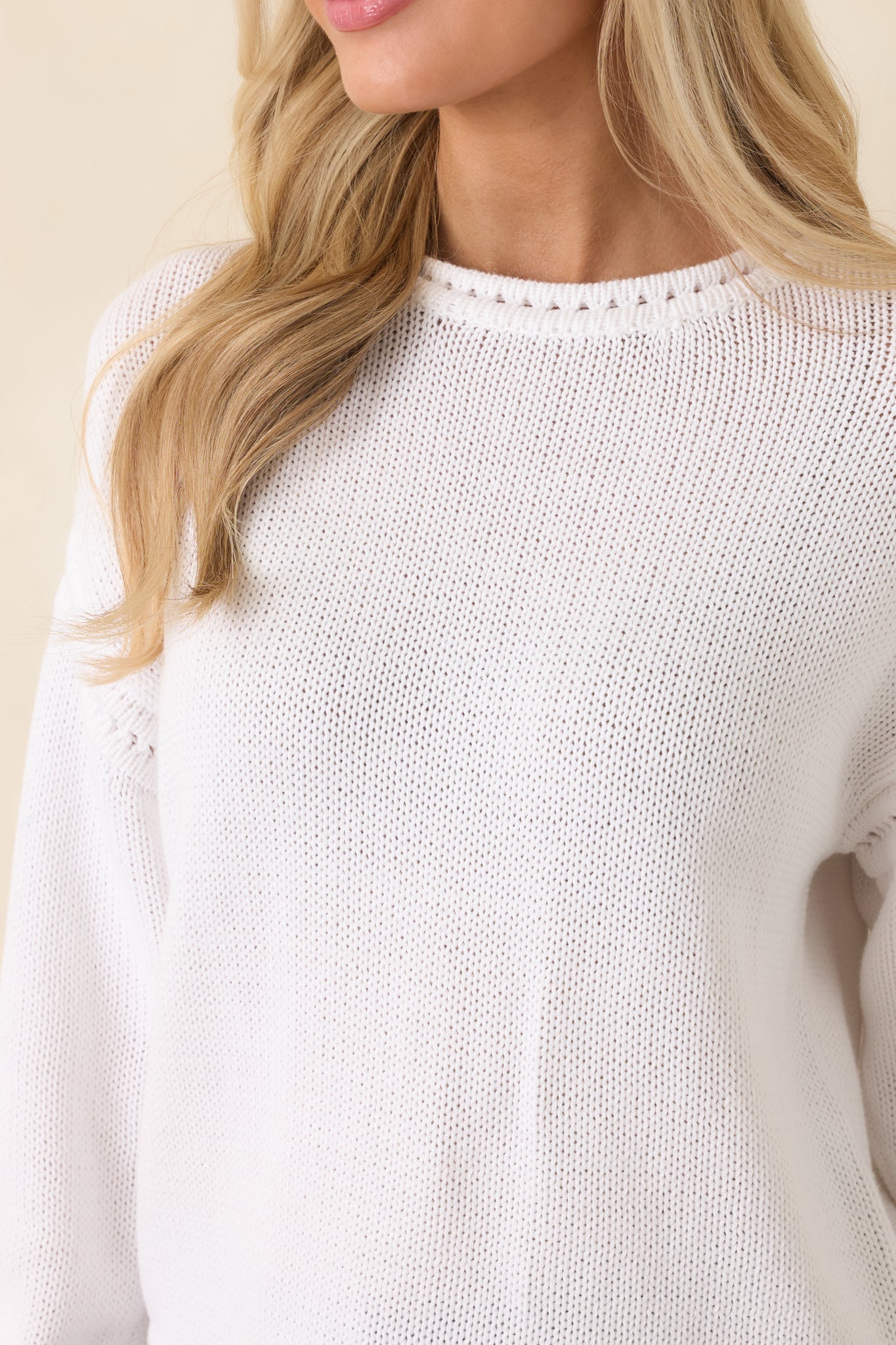 Close-up of white cotton knit fabric featuring delicate open-stitch detailing and ribbed trim finish.
