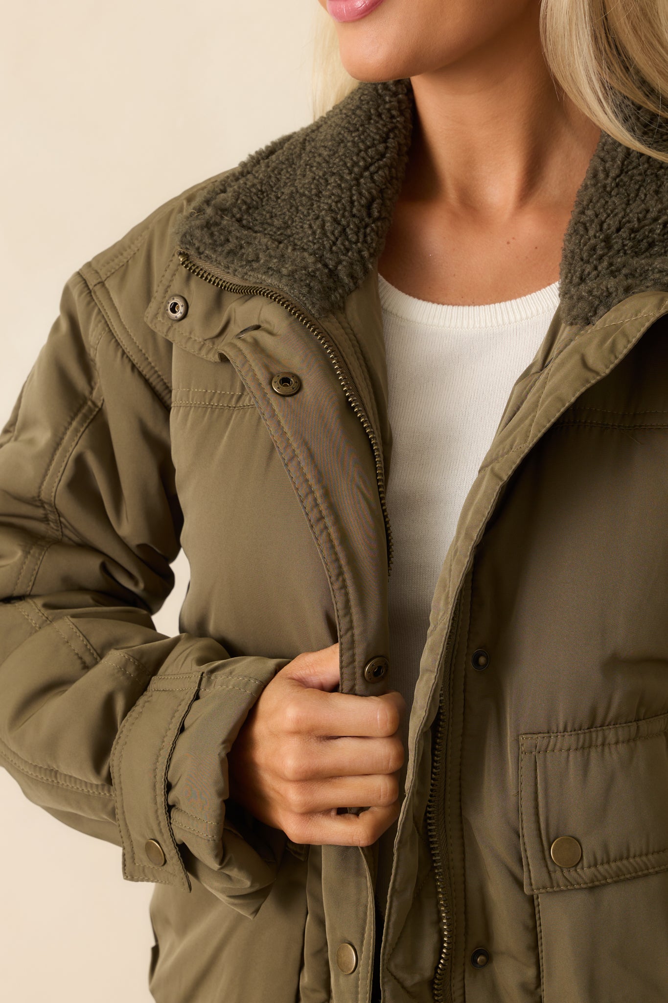 Up-close view of the army green quilted fabric, snap buttons, and sherpa-lined collar.