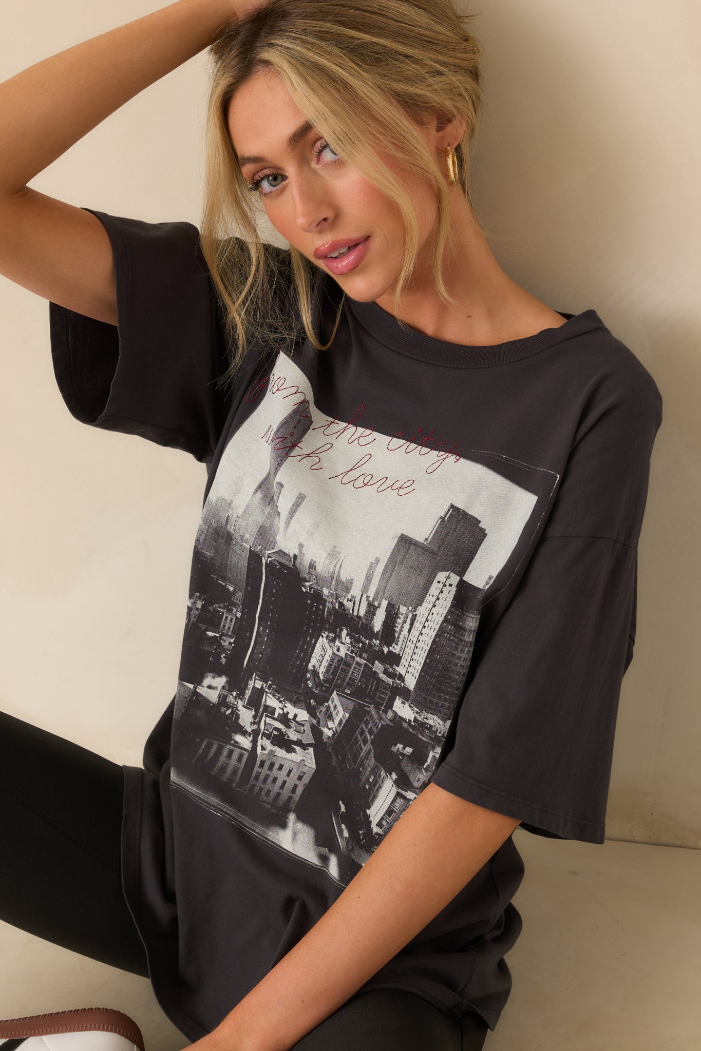 Close view of the black tee’s cityscape print with red cursive embroidery layered on top.