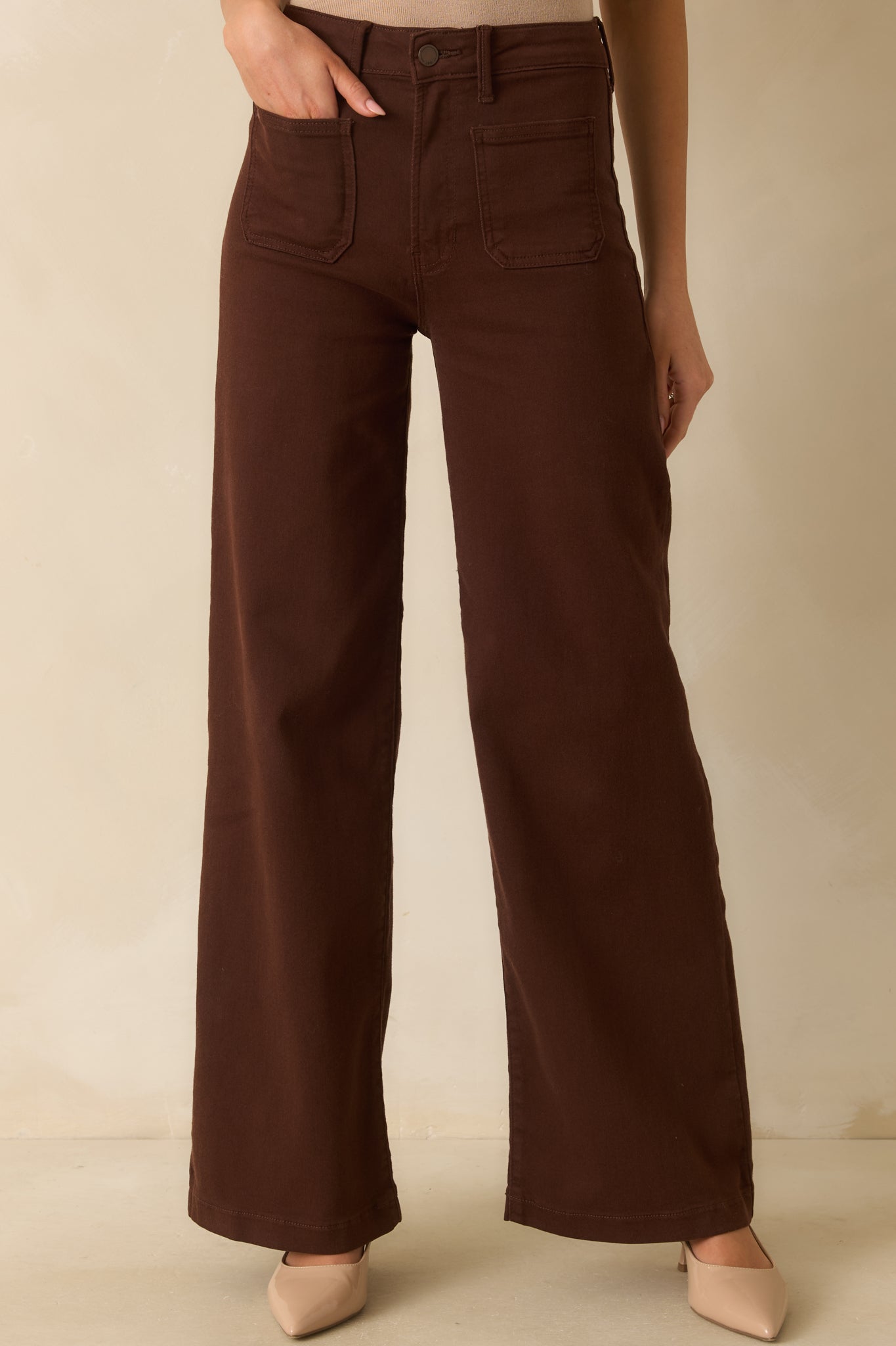 Close view of front patch pockets and belt loops on the brown straight-leg jeans.