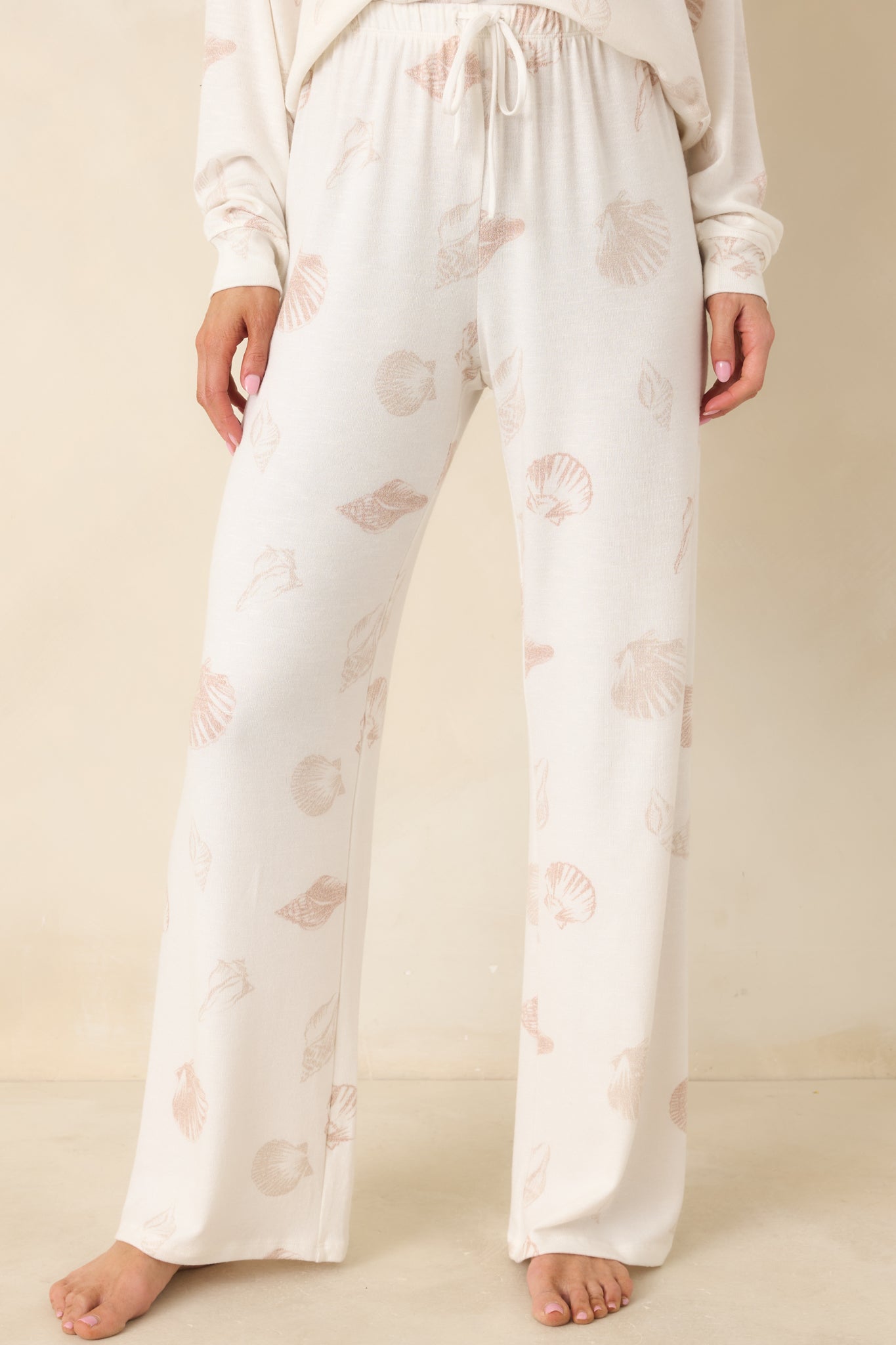 Close view of ivory pajama pants highlighting elastic waistband with adjustable drawstring and relaxed drape through the hips.