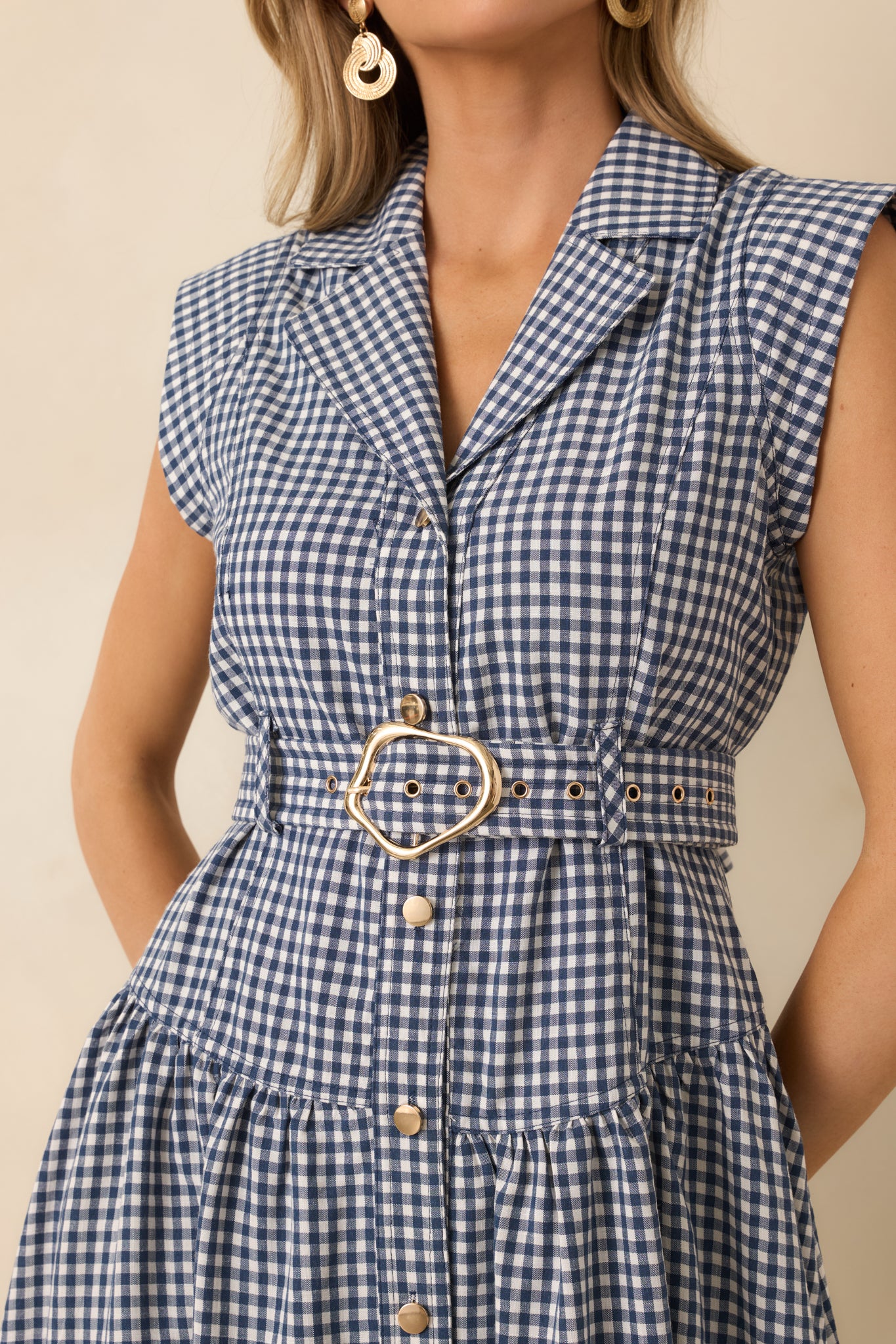Close view of the navy gingham dress showing the coordinating buttons, belt buckle, and fine checkered woven texture.