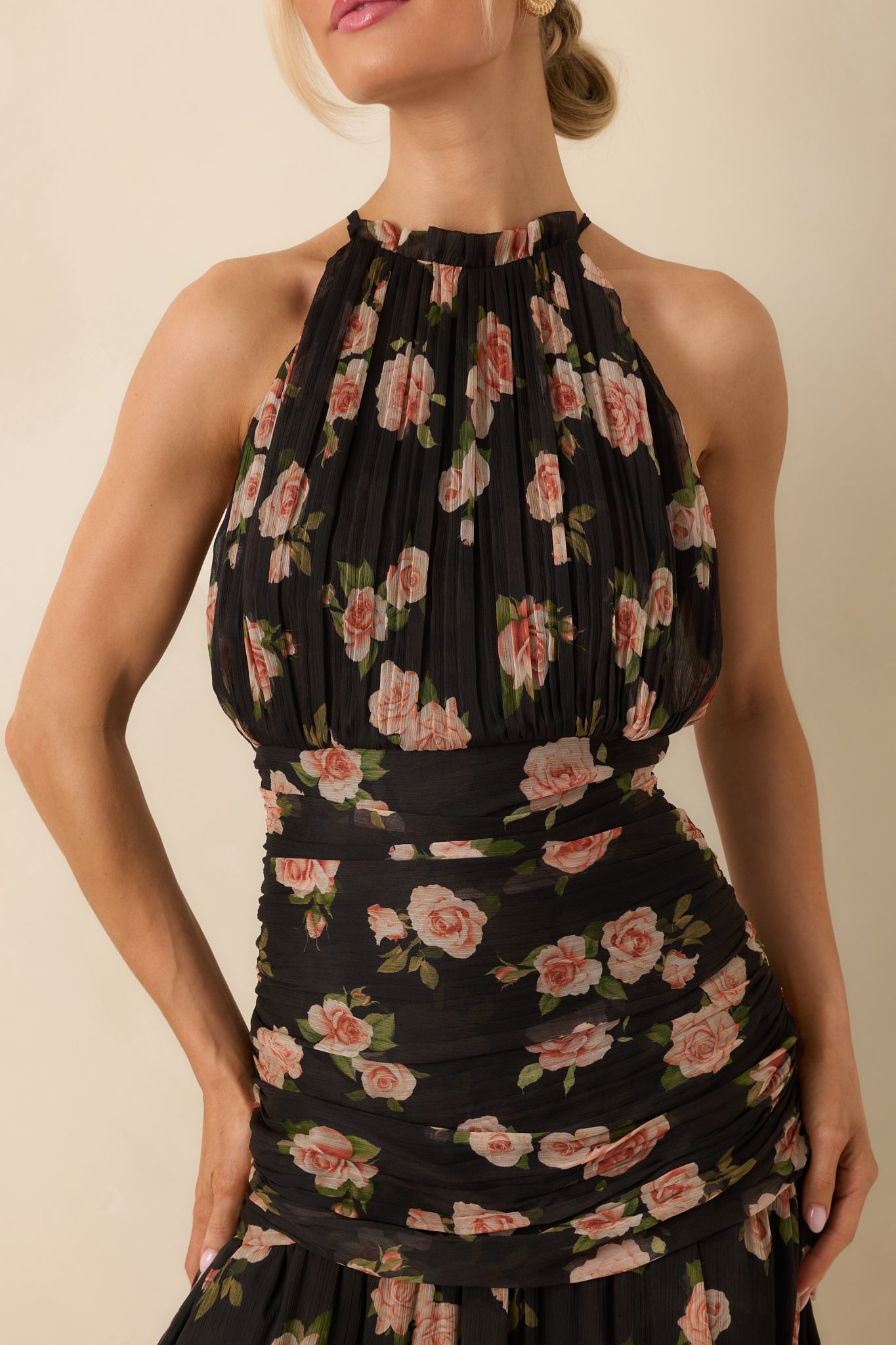 Close view of chiffon pleats on black fabric with soft floral print in blush and muted green tones.