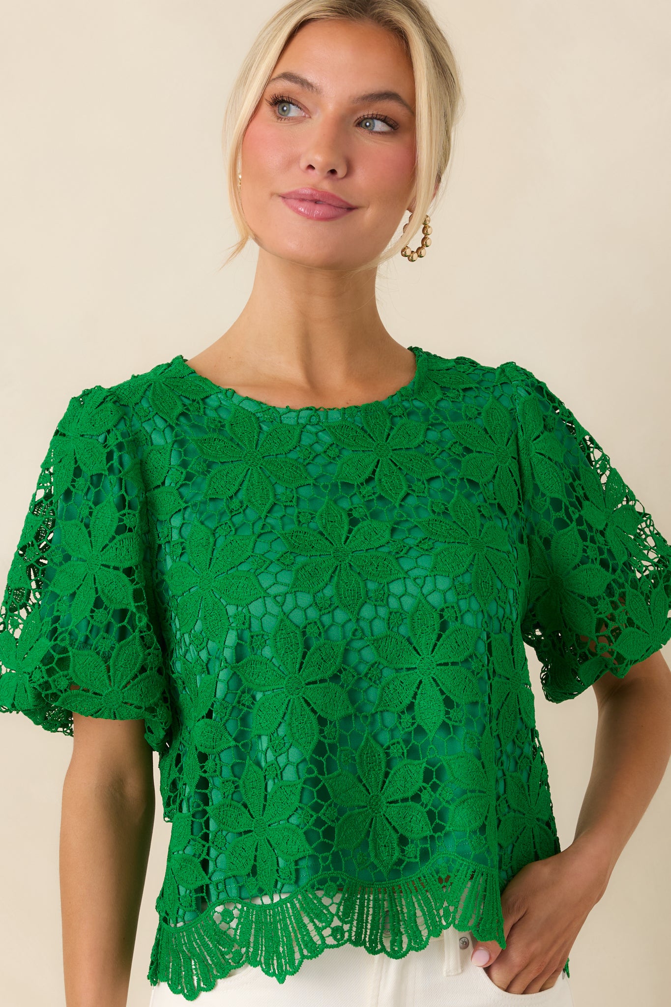 Close view of green crochet lace top with scalloped edge detail.