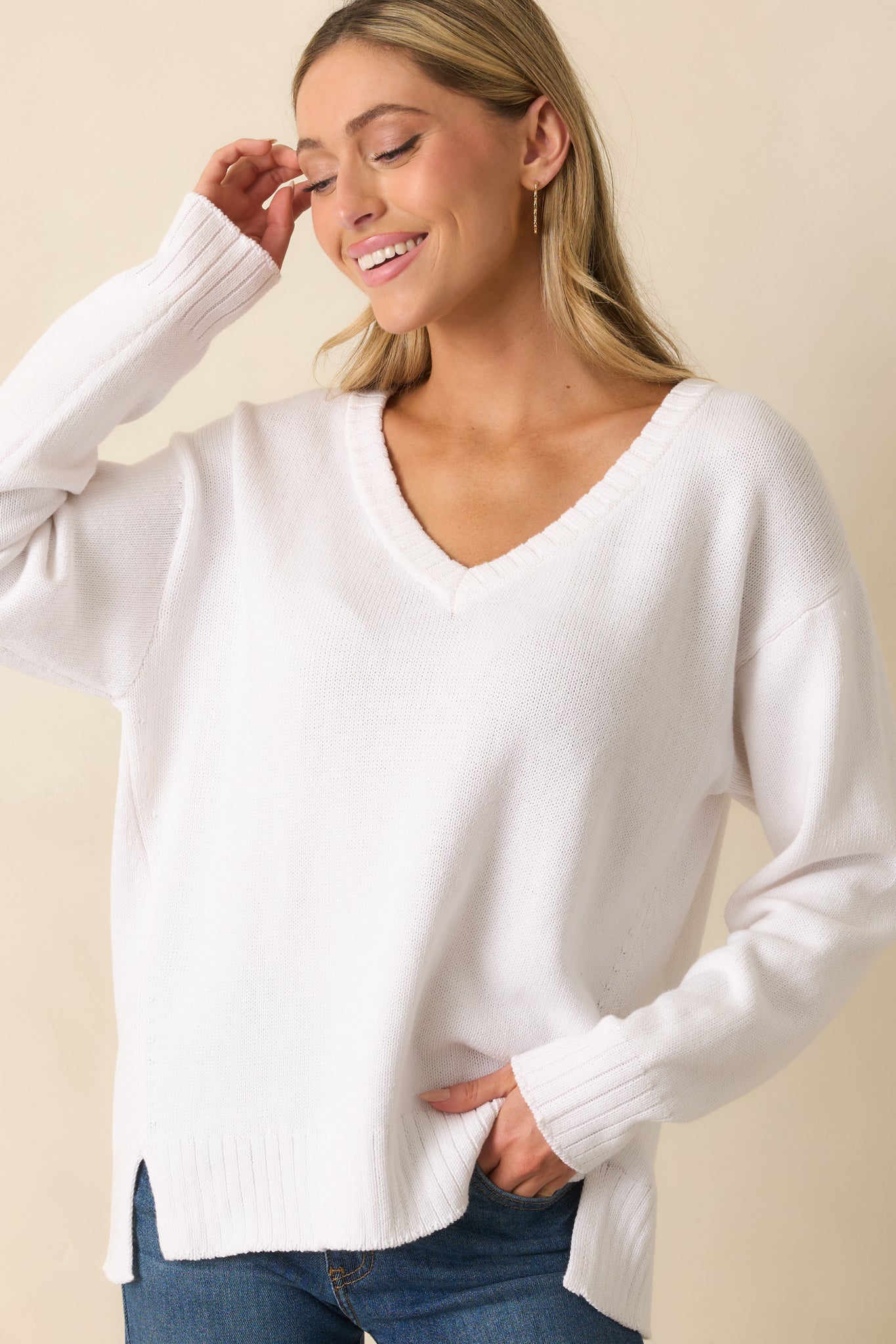Close view of hem and sleeve ribbing highlighting the fabric texture of the white sweater.