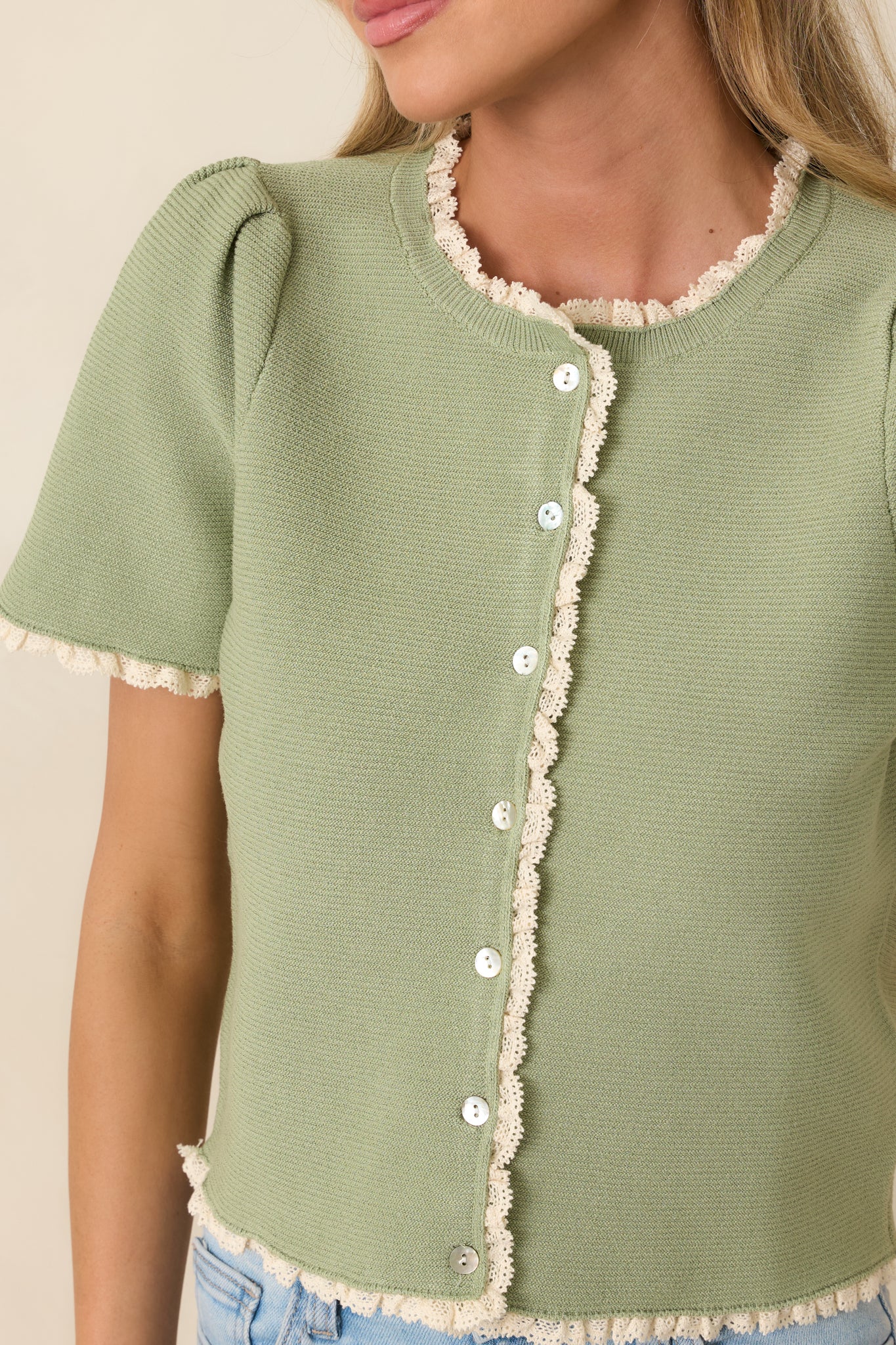 Close view of lace trim and button detailing along knit neckline and placket.