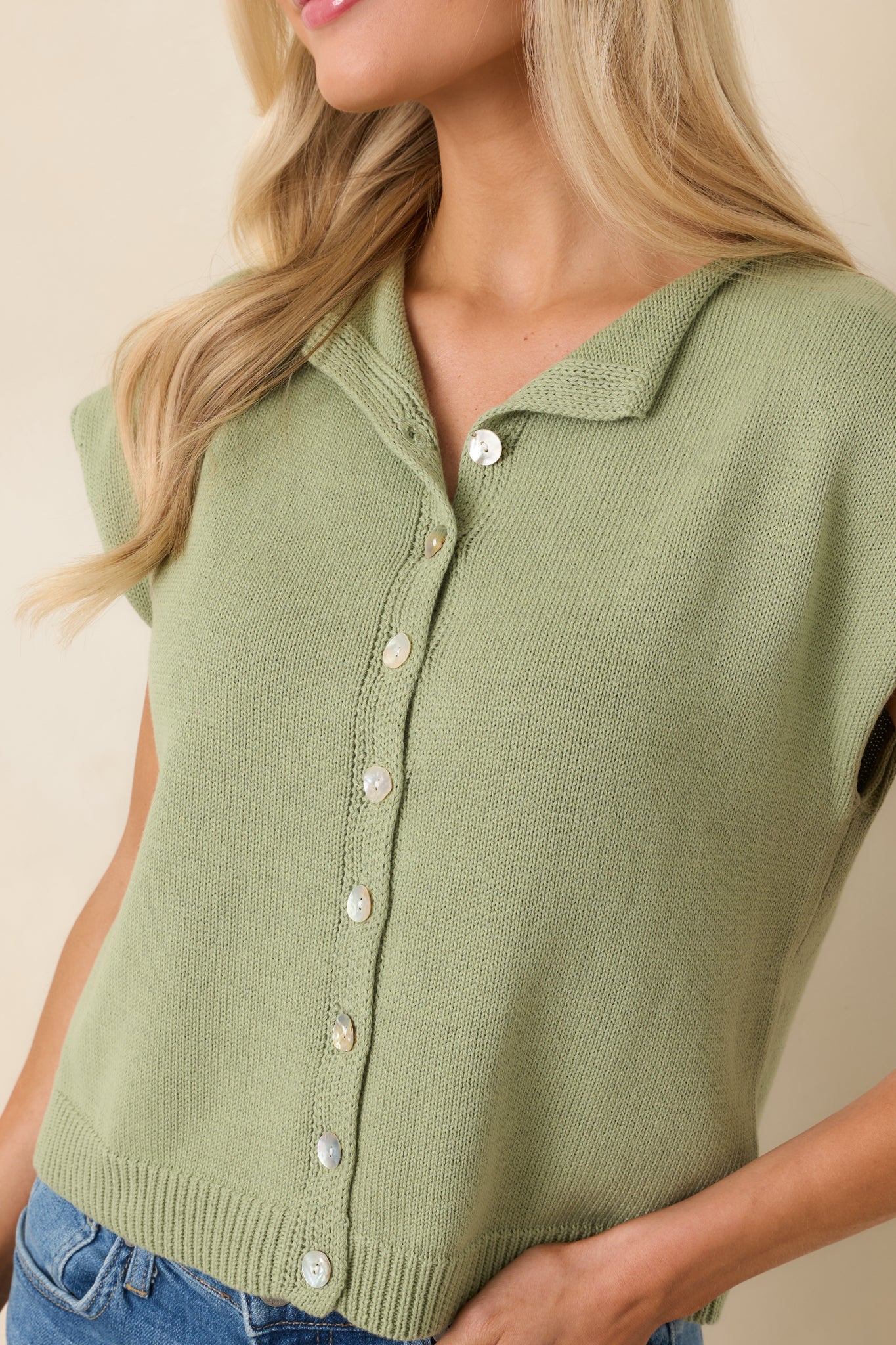 Close view of pearlescent-style buttons and knit texture on green top.