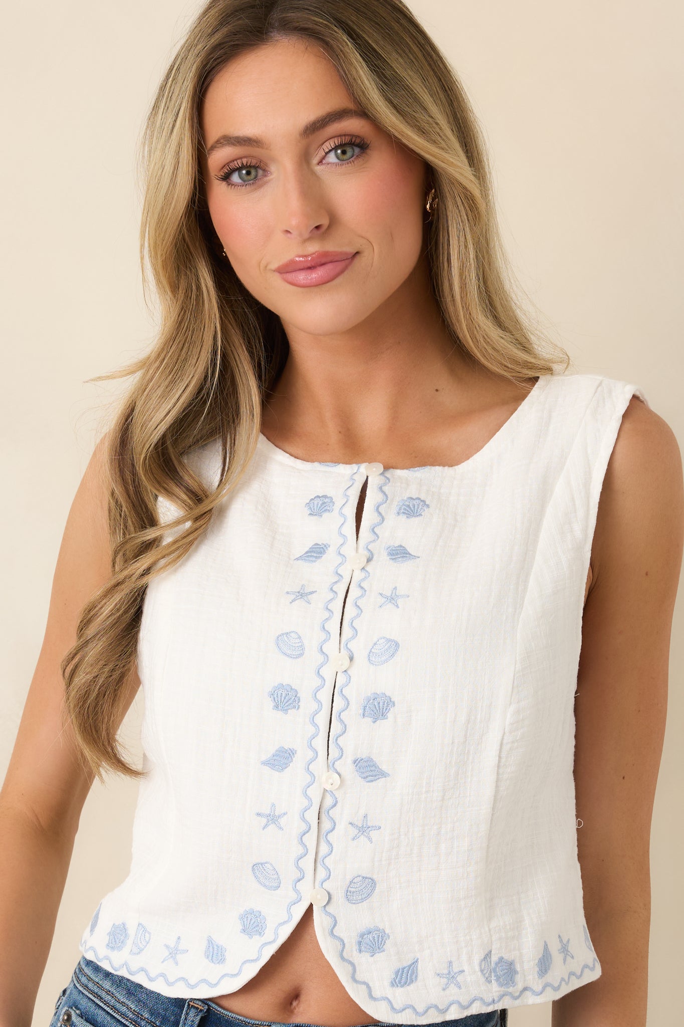 Close view of sleeveless ivory top with lightweight cotton texture.