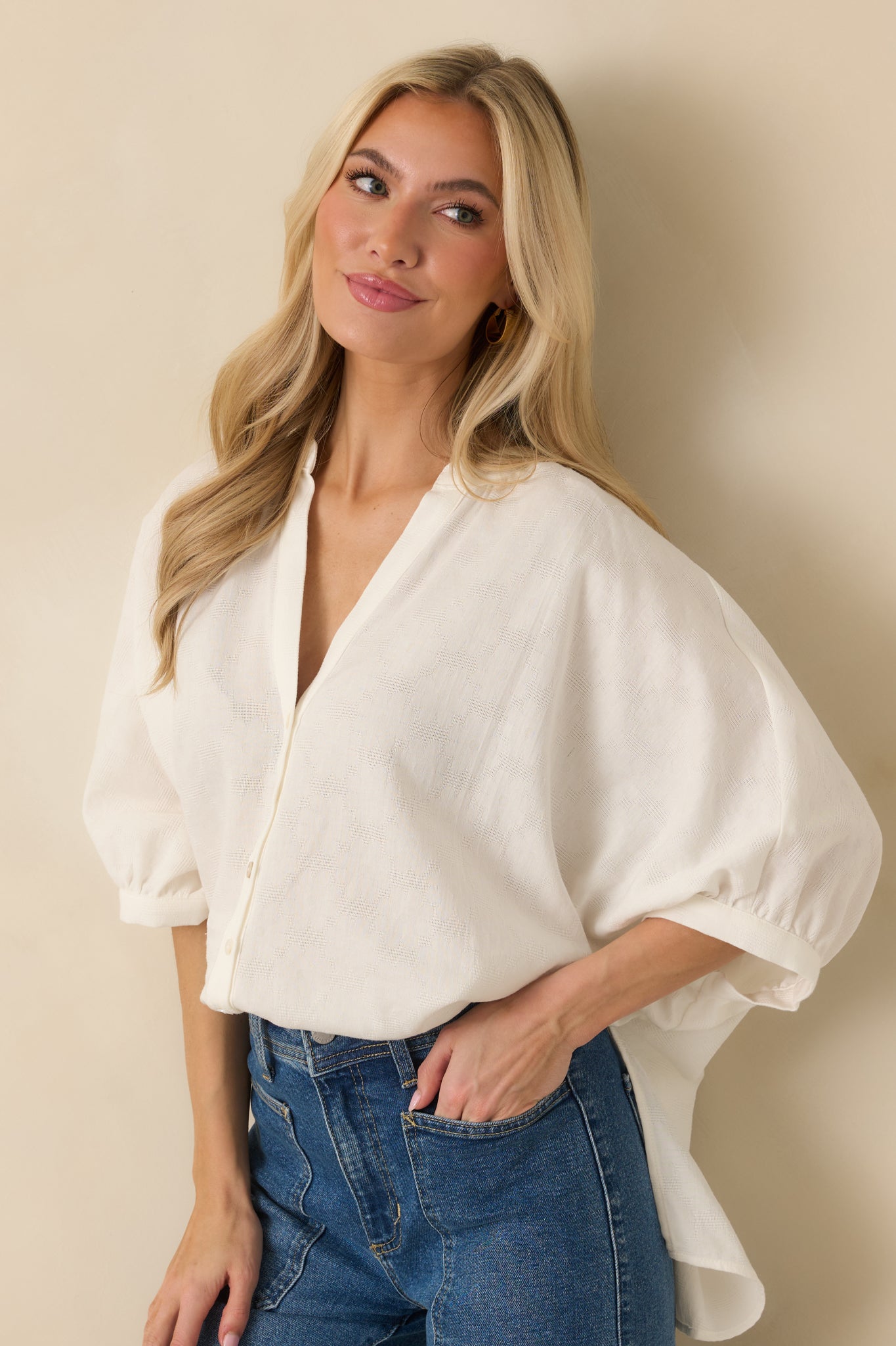 Close view of split neckline and button-front closure with relaxed knit drape.