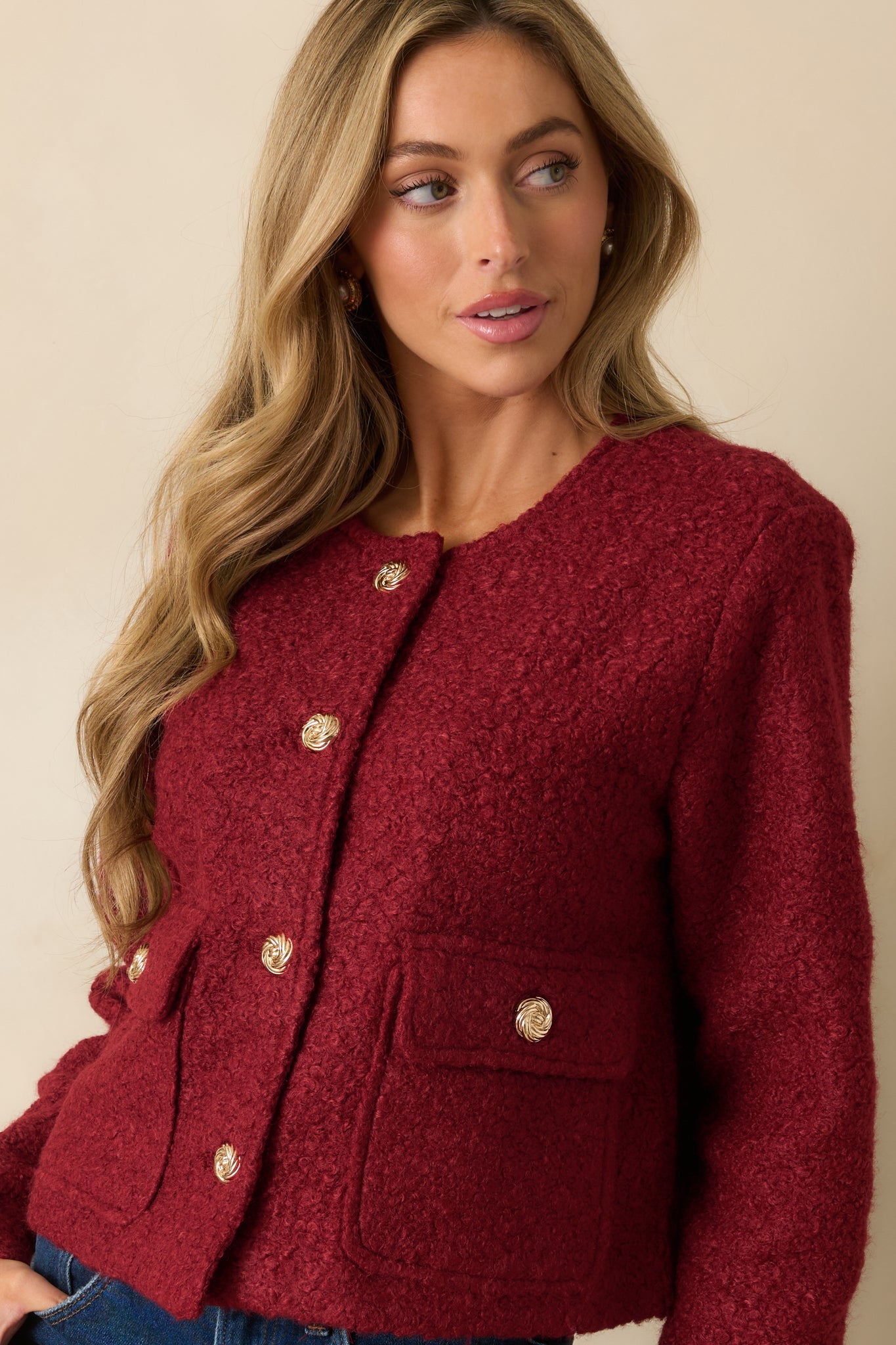 Close view of the jacket’s front flap pockets and gold button closures.