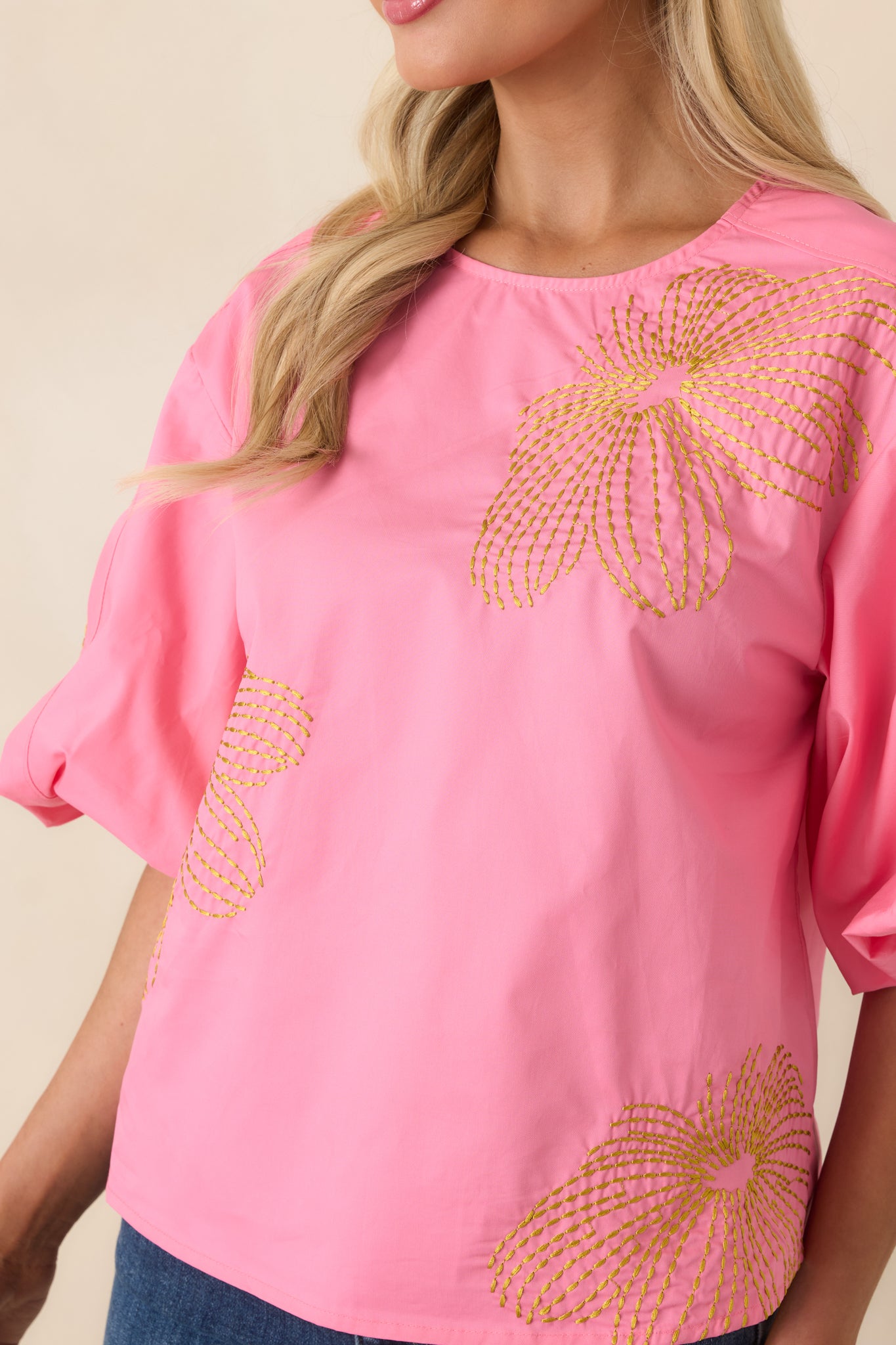 Close view of the round neckline and intricate green embroidery on breathable cotton.