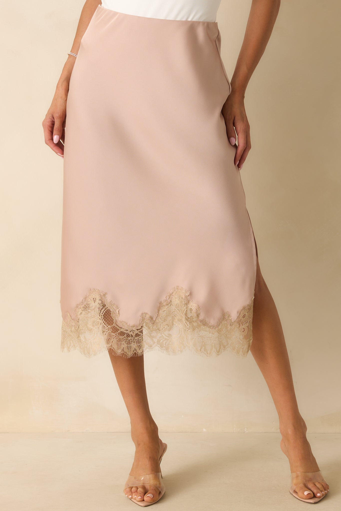 Close view of the high-rise elastic waistband and smooth satin fabric of the dusty pink skirt.