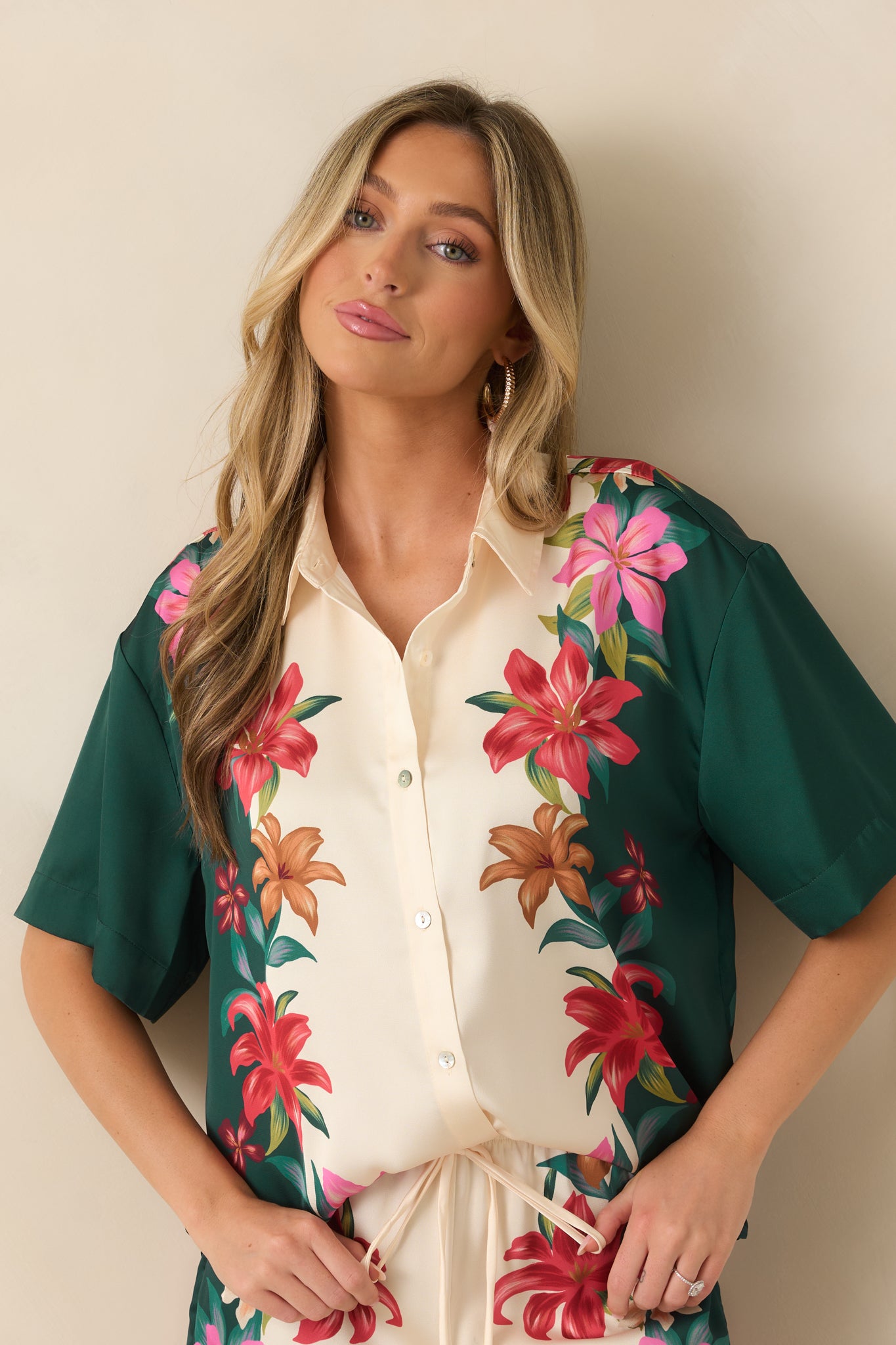 Close view of the teal floral satin top highlighting the collared neckline, button-front closure, and silky texture.