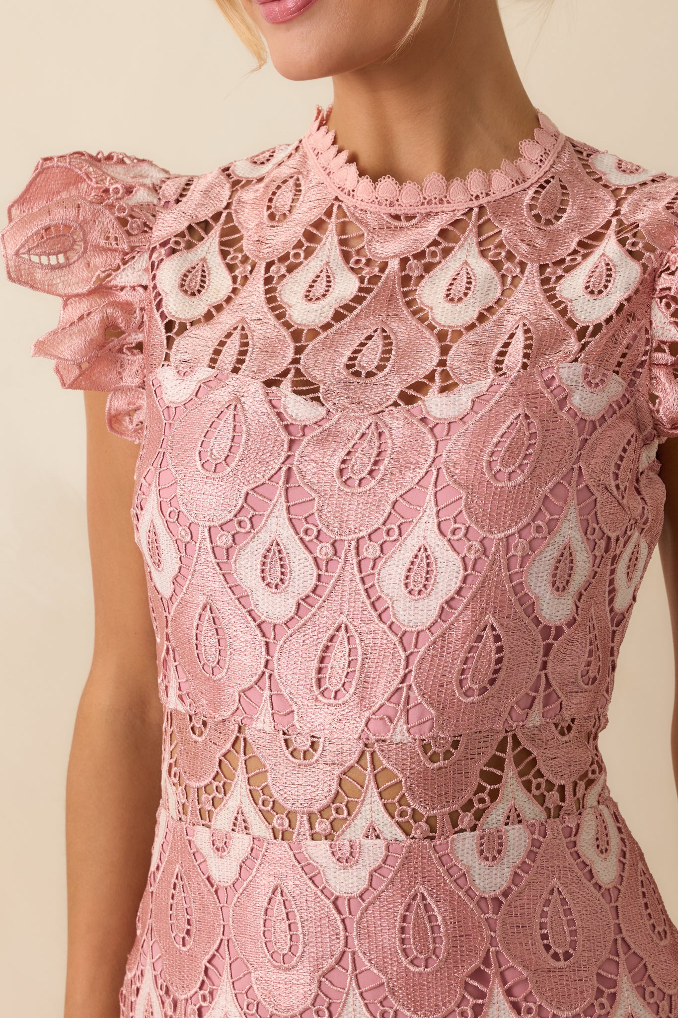A close view reveals the intricate lace pattern, scalloped edging, and sheer lace insets on the soft pink fabric.