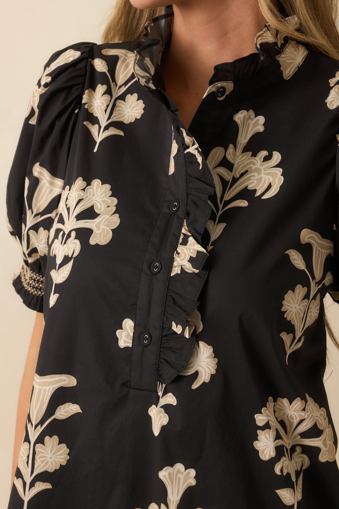 Close view of the ruffled mock neckline, button placket, and puff sleeve detailing with smocked cuffs.