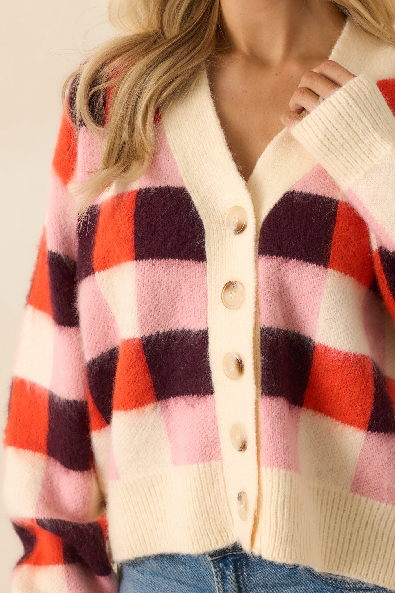 A close view shows the fuzzy knit texture, vibrant pink check pattern, and precise ribbed trim along the edges