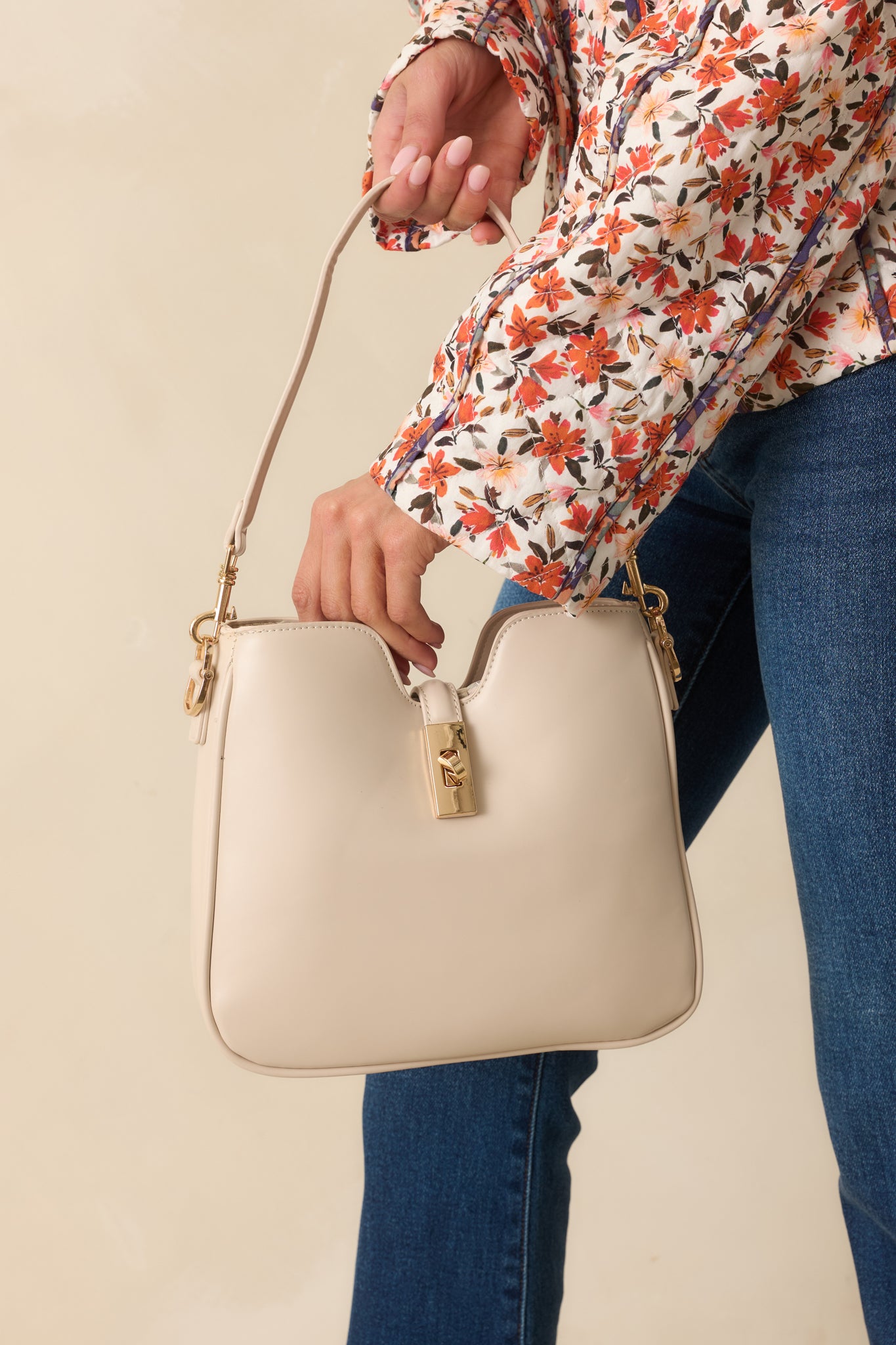 Close view of the top v-cut edge and turn lock closure on the ivory structured bag.