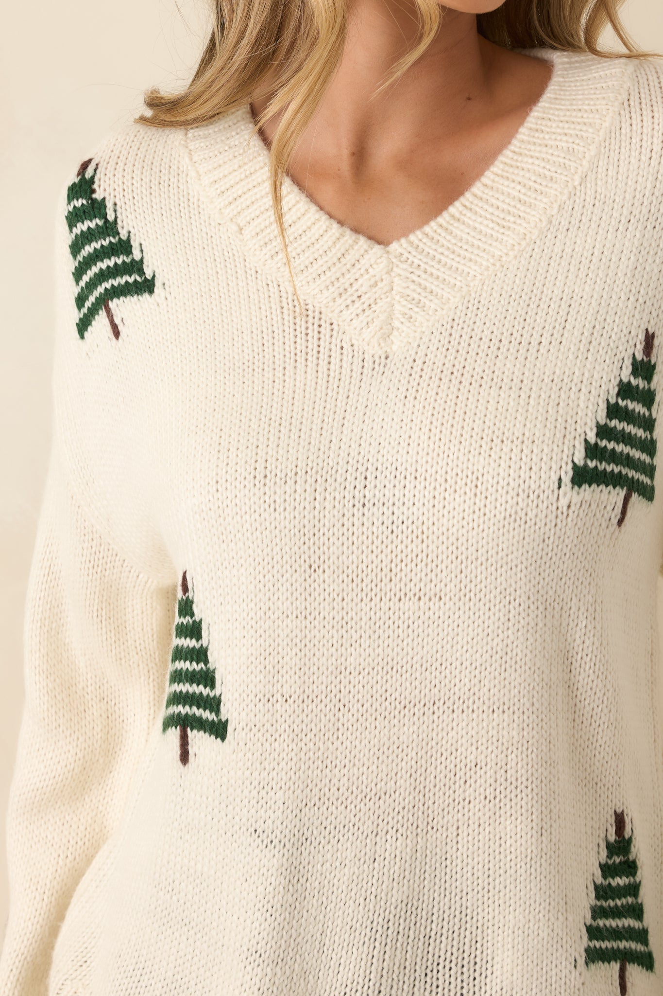 Close view of the sweater’s V-neckline framed by tidy ribbing and subtle pine motifs.